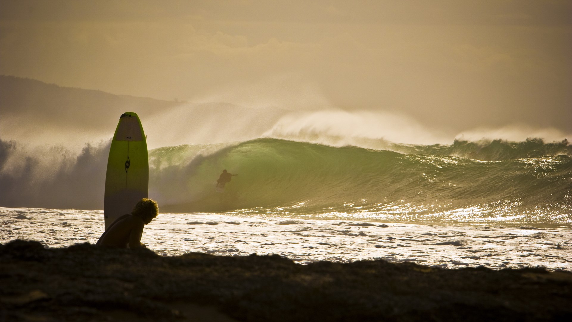 Surfer riding a wave with a child and surfboard on the beach HD Wallpaper