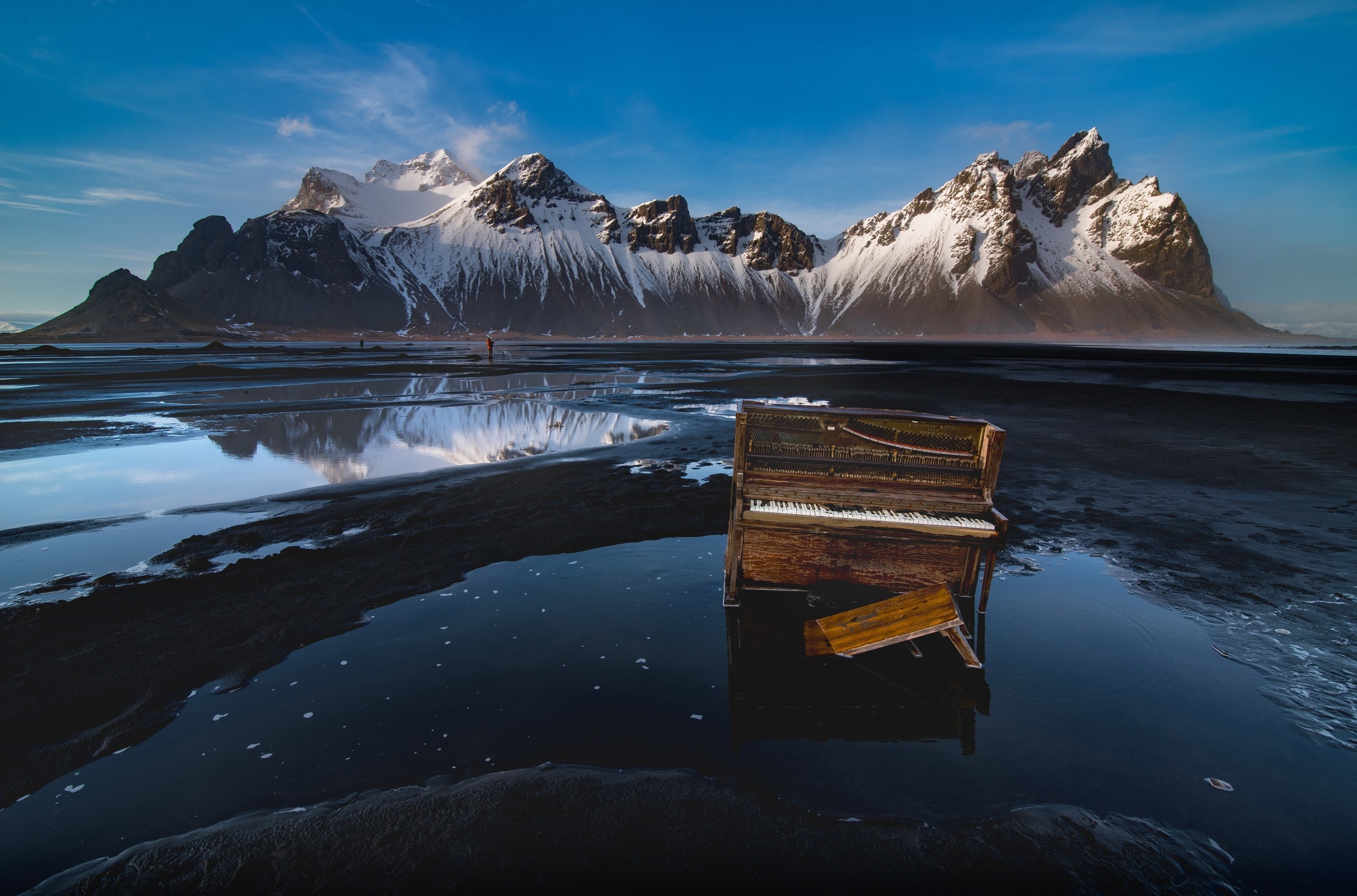 Old piano on a black sand beach with snowy mountains HD Wallpaper