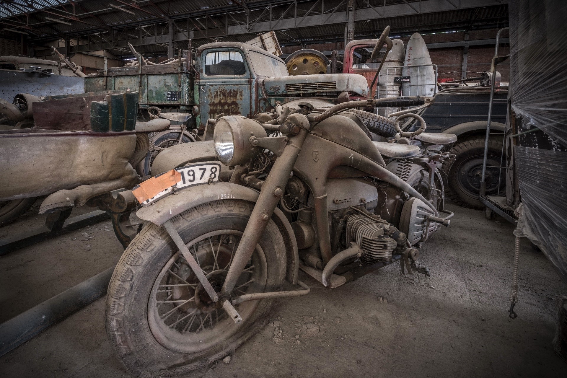 Dusty old motorcycle and trucks in a warehouse HD Wallpaper