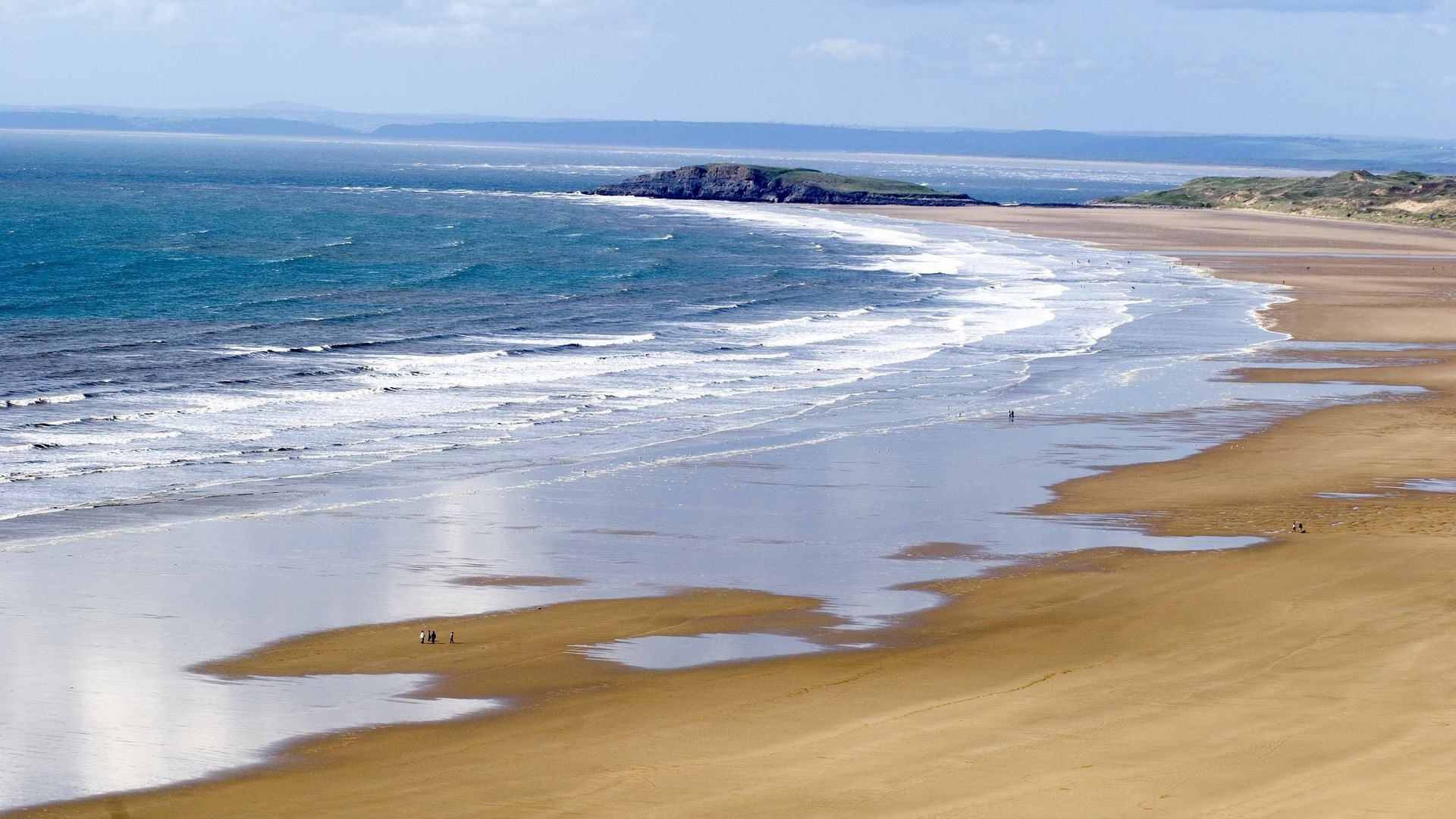 Sandy beach with waves and distant island HD Wallpaper