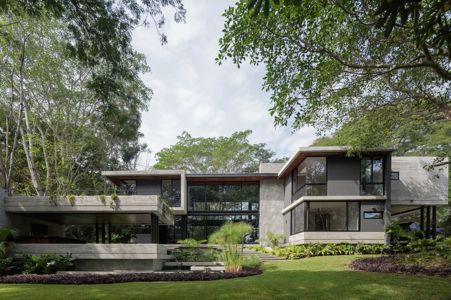 Modern concrete house with large windows surrounded by trees HD Wallpaper
