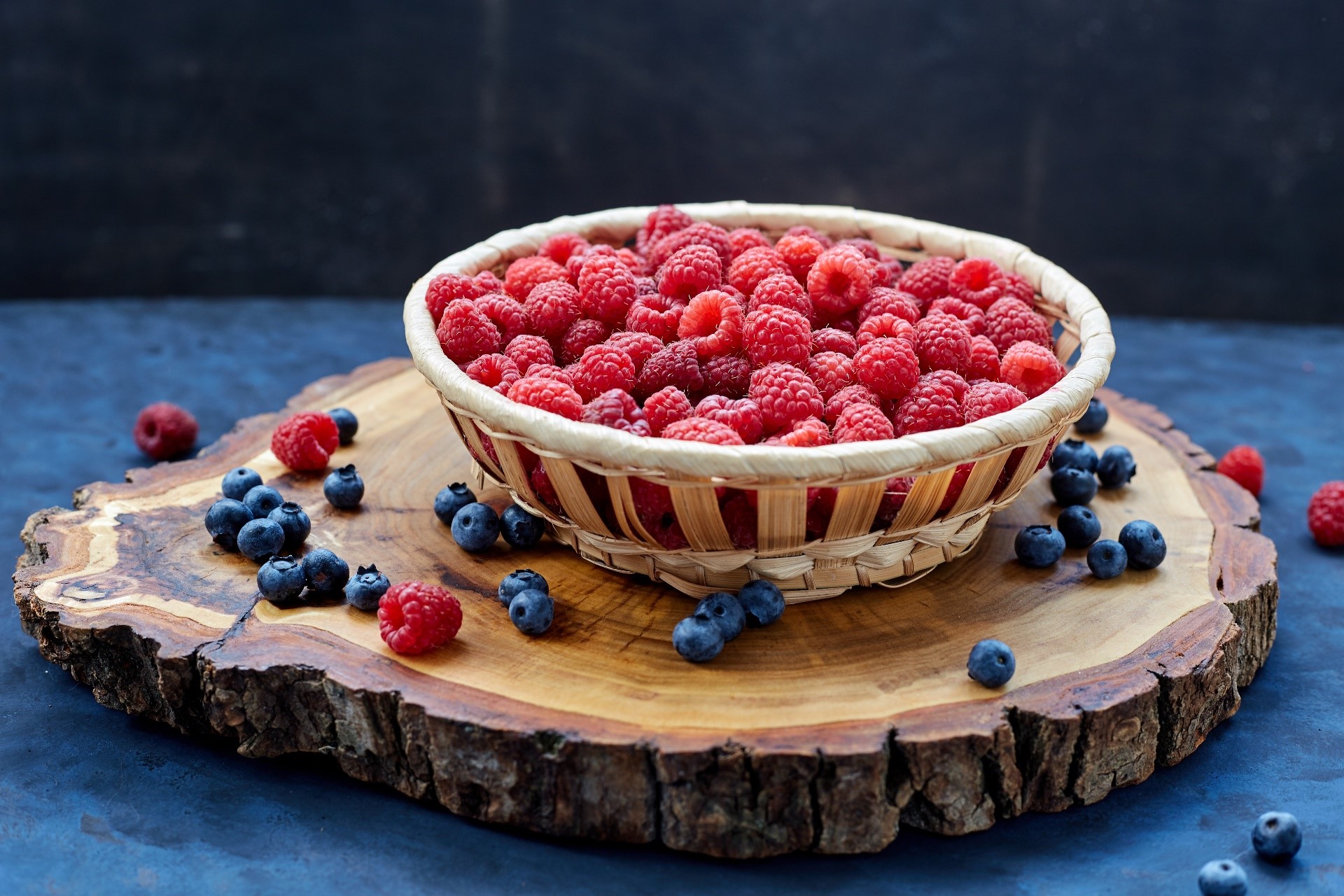 Basket of raspberries and blueberries on a wooden slice HD Wallpaper