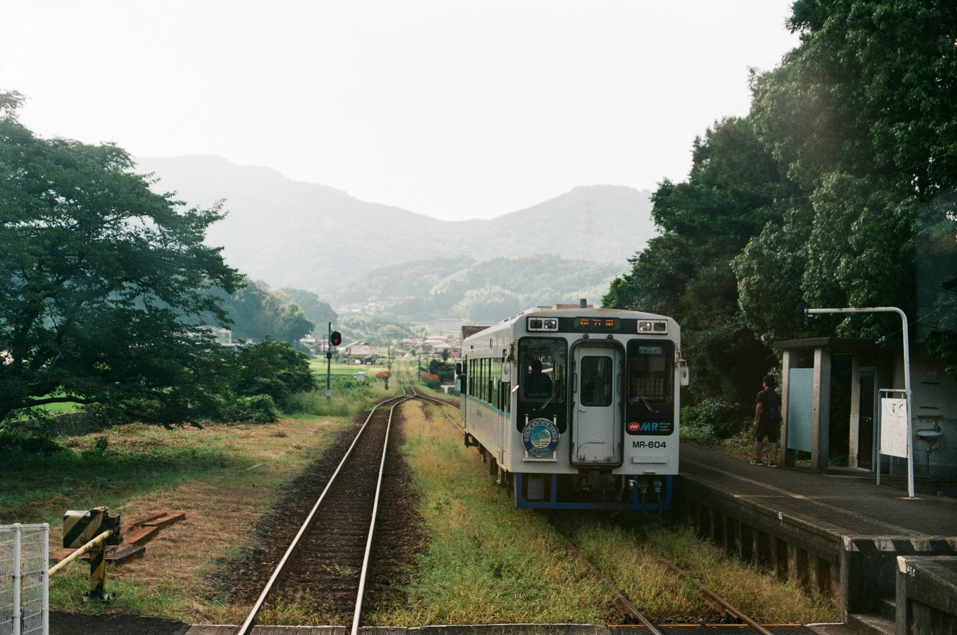Train at a rural station with mountains in the background HD Wallpaper