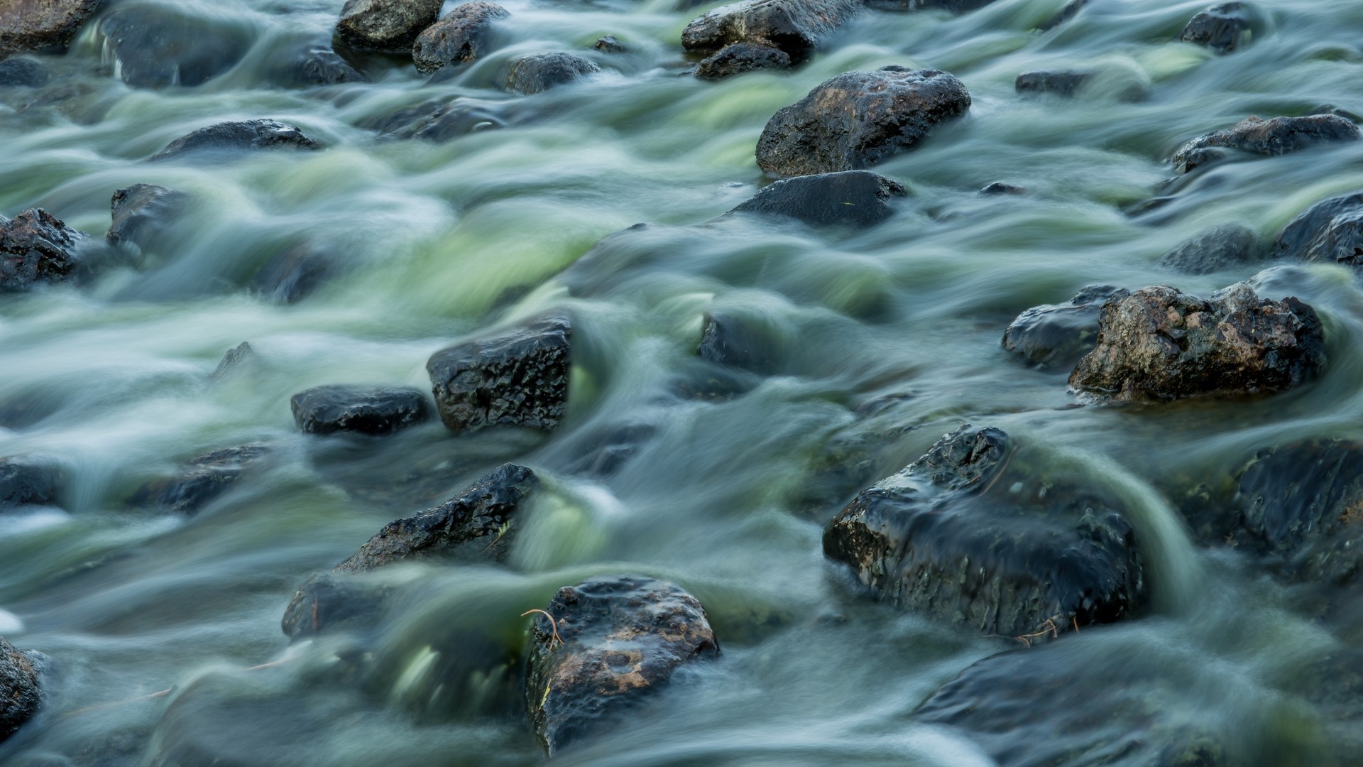 Long exposure of water flowing over rocks HD Wallpaper