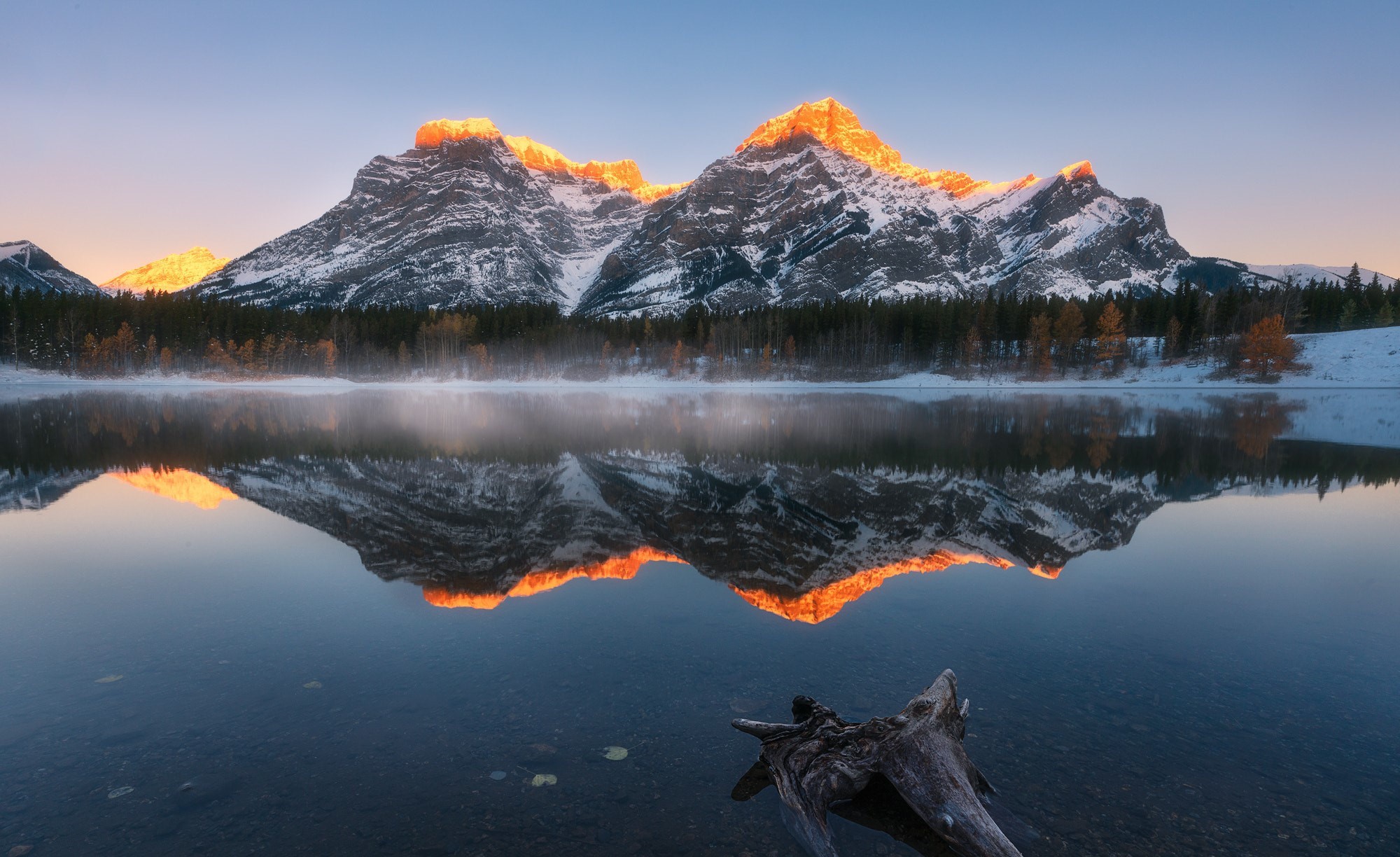 Snow-capped mountains reflected in a calm lake at sunrise HD Wallpaper