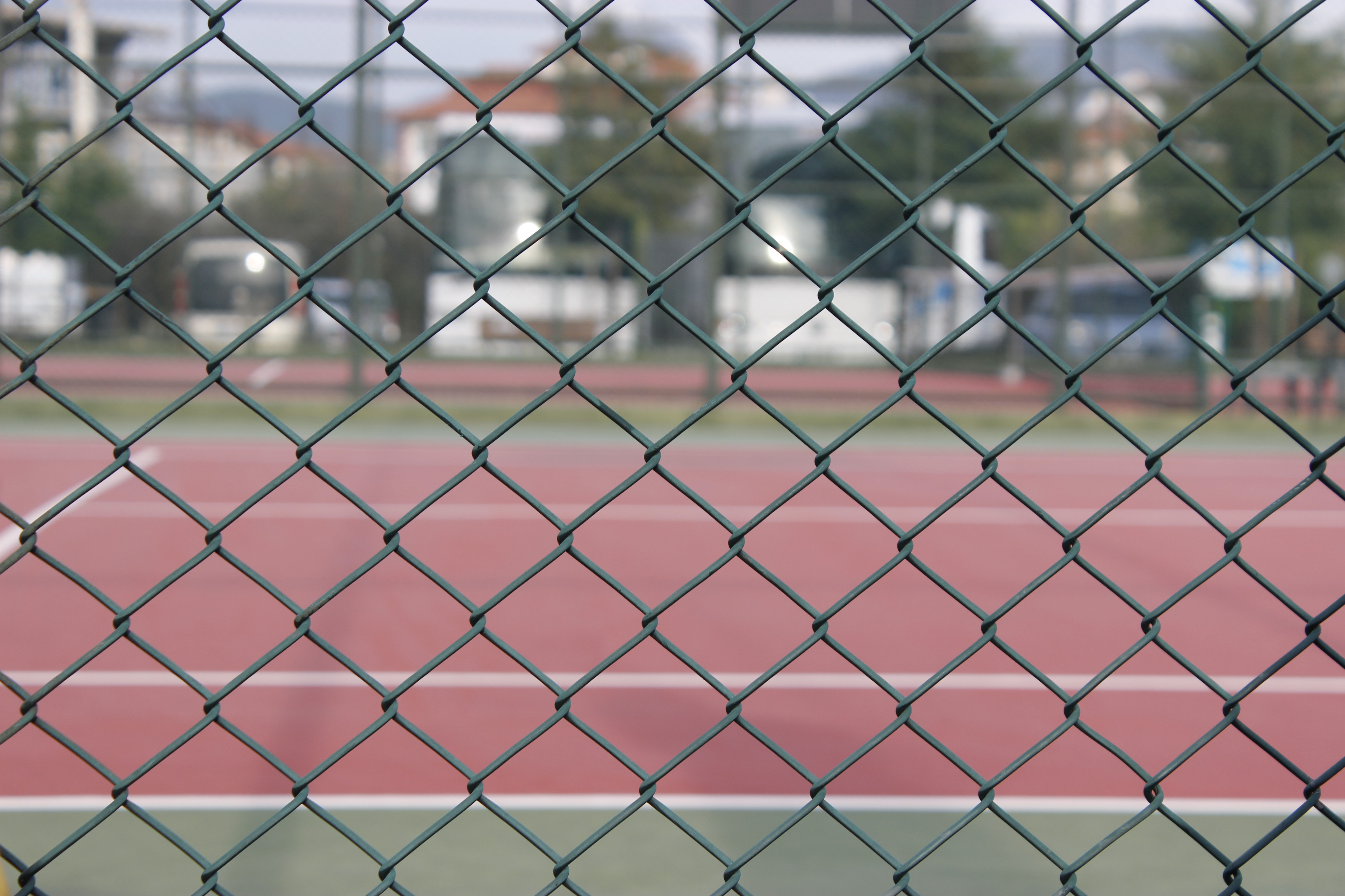Chain-link fence in front of a tennis court HD Wallpaper