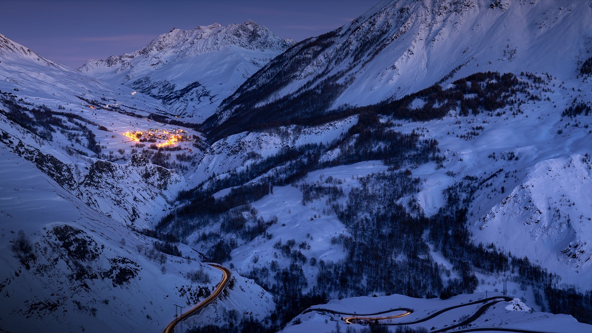 Snowy mountain valley with village and winding road HD Wallpaper