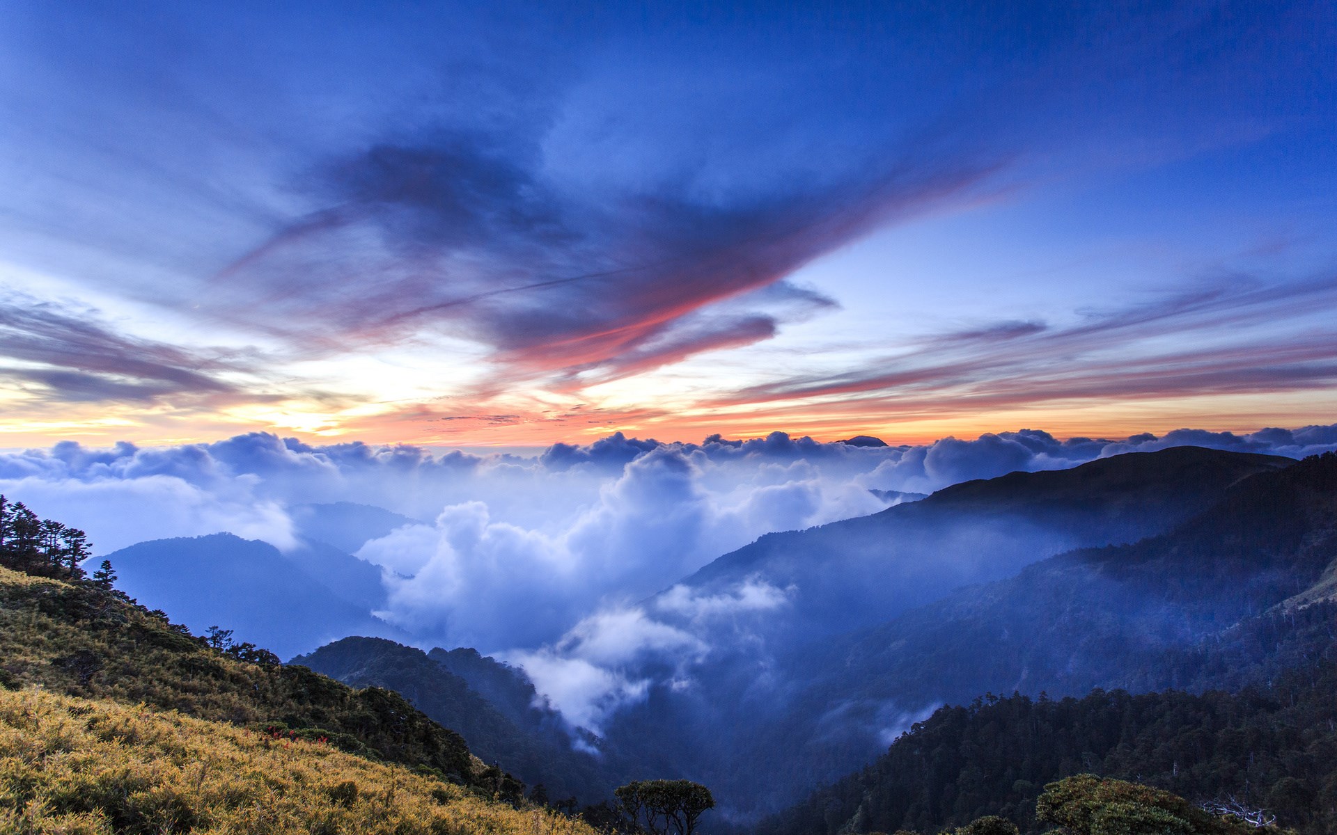 Mountain range covered in clouds at sunset HD Wallpaper