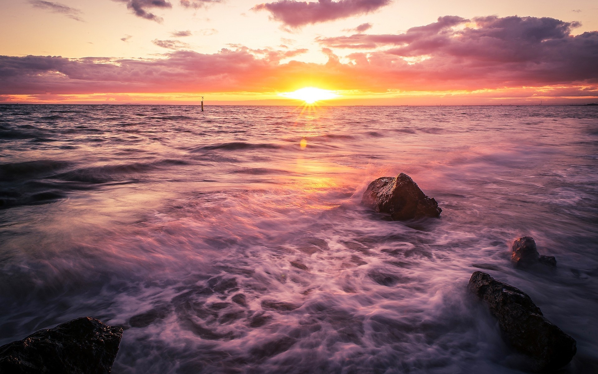 Sunset over the ocean with rocks on the shore HD Wallpaper
