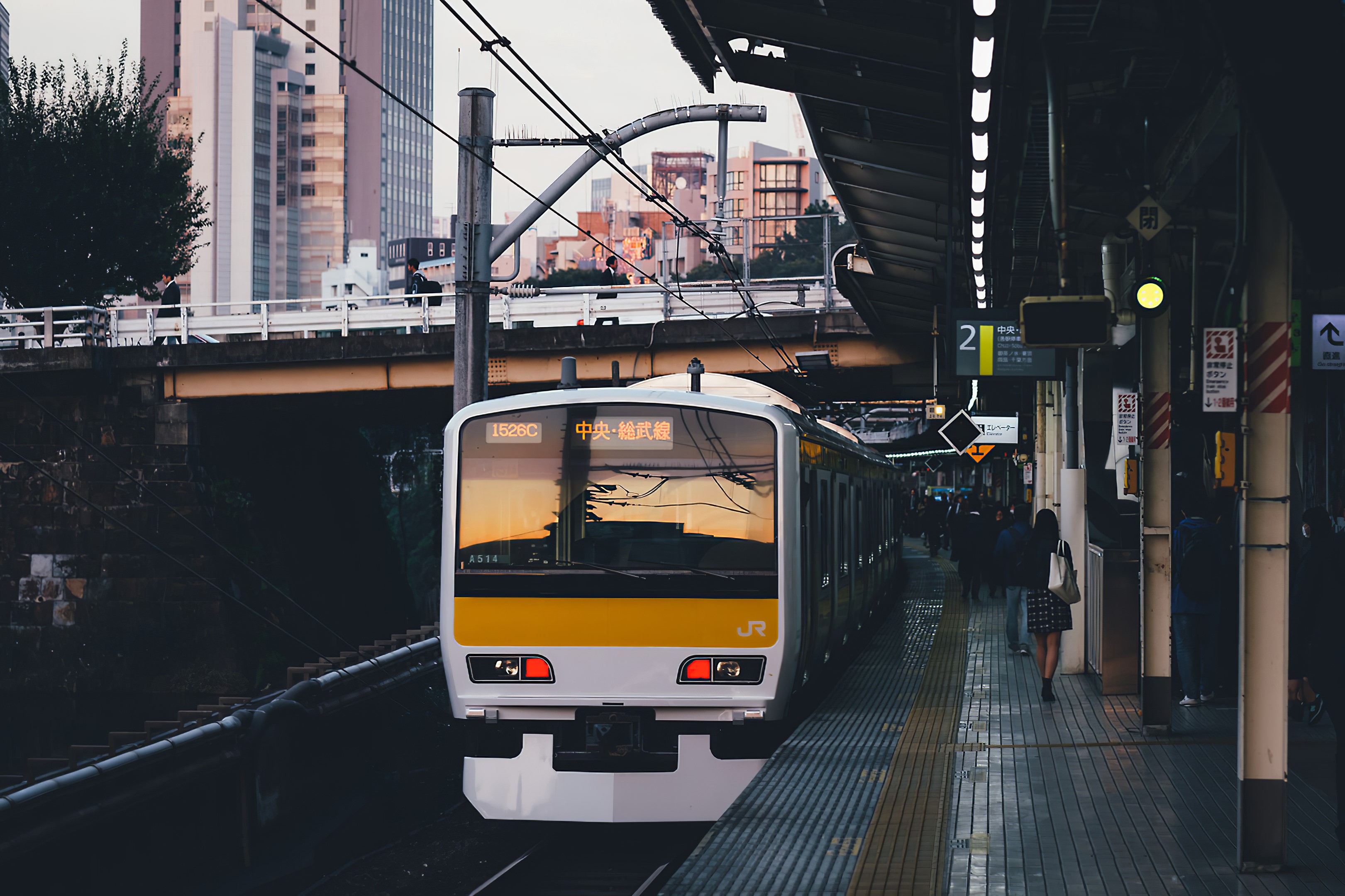 Train at a Japanese station with buildings in the background HD Wallpaper