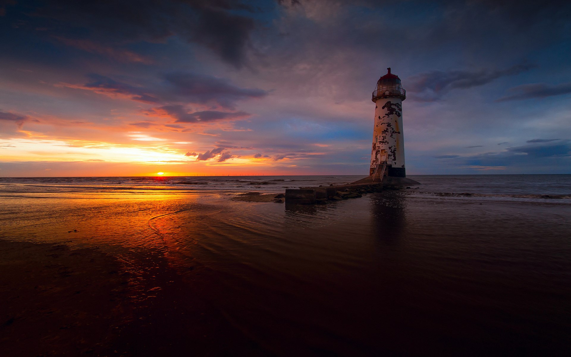 Lighthouse on a beach at sunset HD Wallpaper