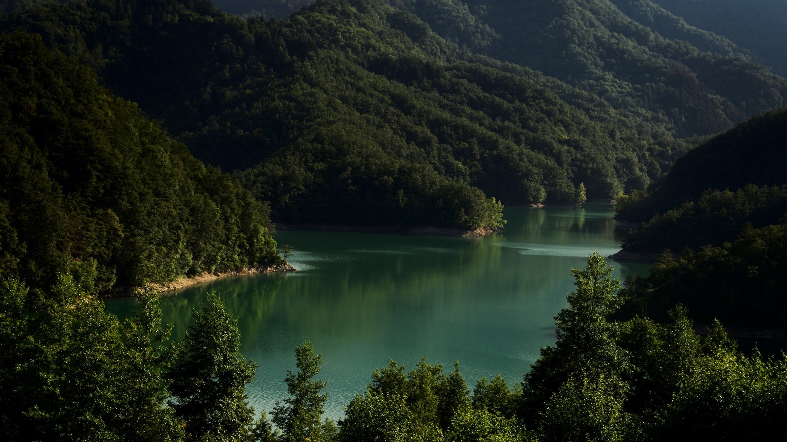 Green mountains surrounding a tranquil lake HD Wallpaper