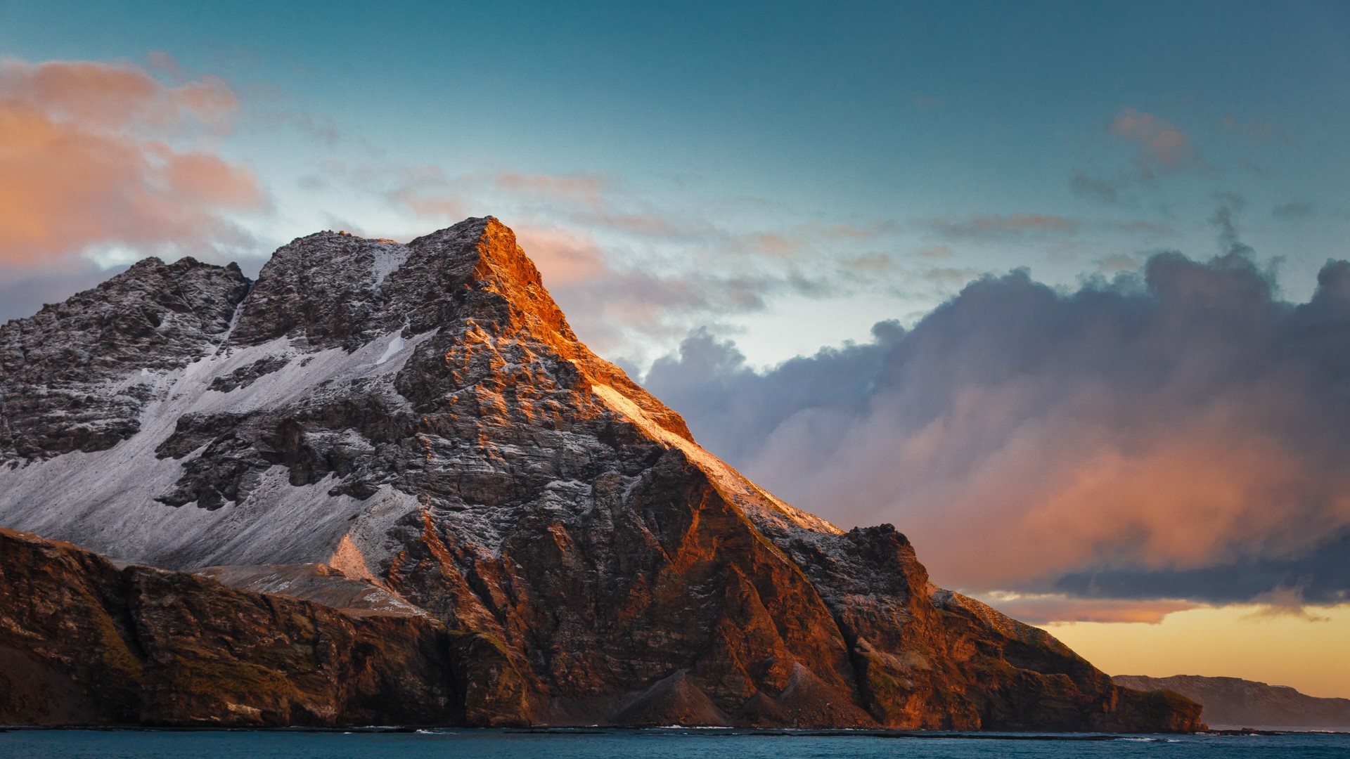 Snowy mountain range at sunset over the ocean HD Wallpaper