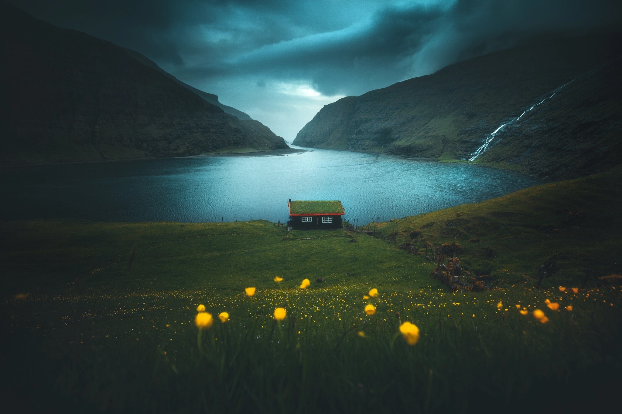 A small house with a green roof by a fjord HD Wallpaper