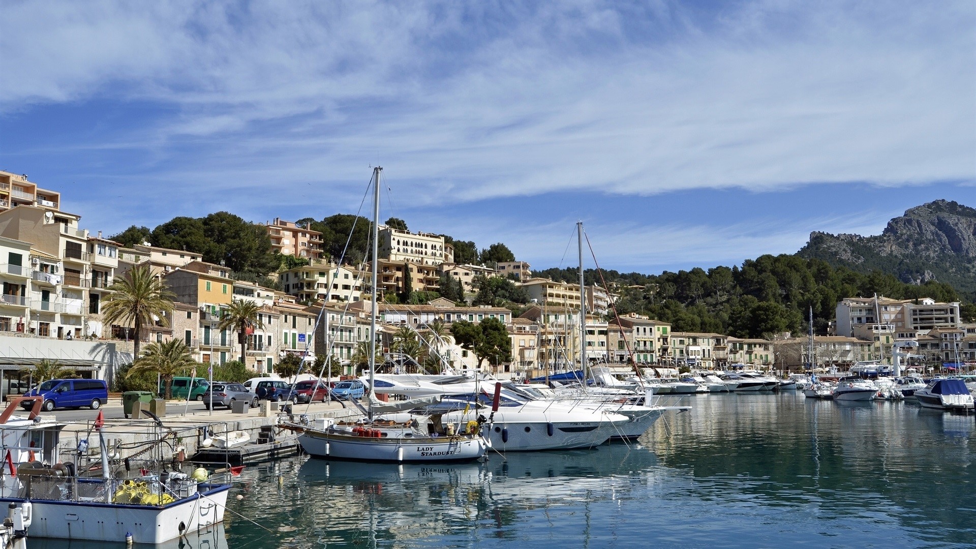 Boats docked in a harbor with buildings on a hillside HD Wallpaper