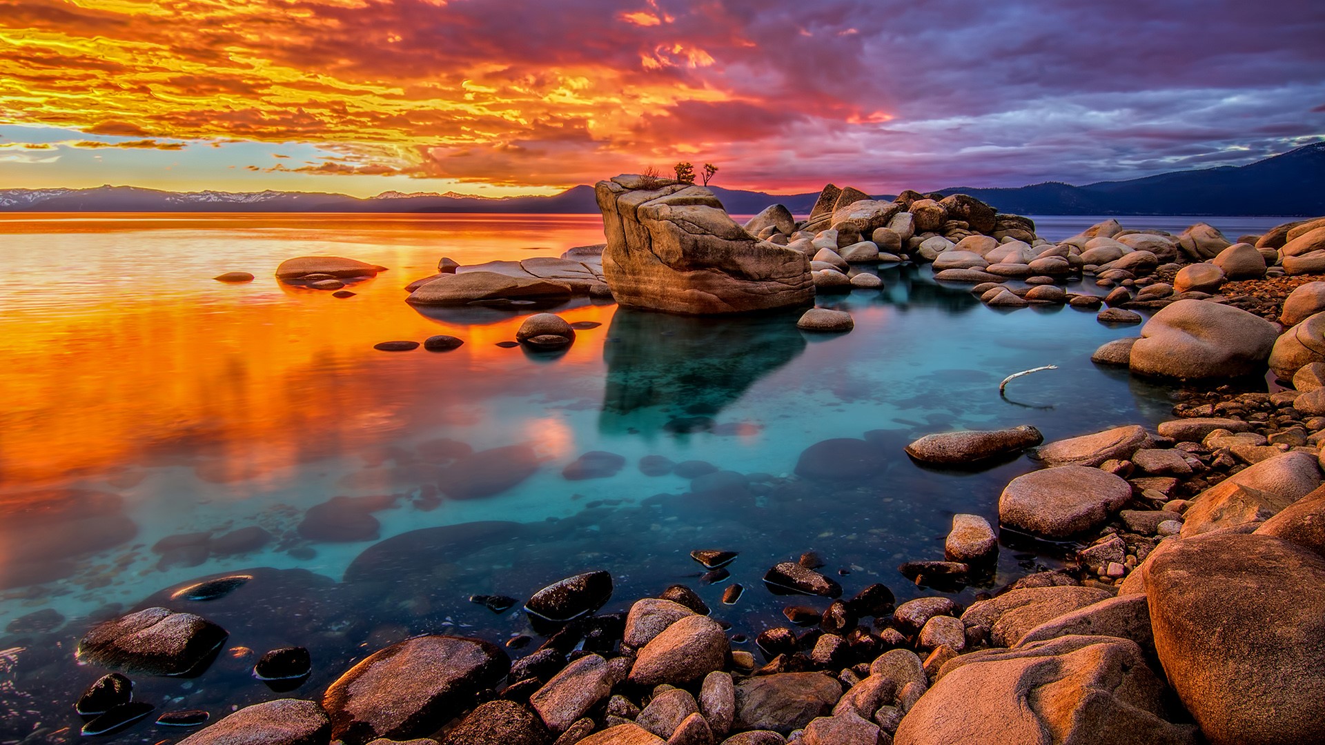 Lake Tahoe at sunset with rocky shore and mountains HD Wallpaper