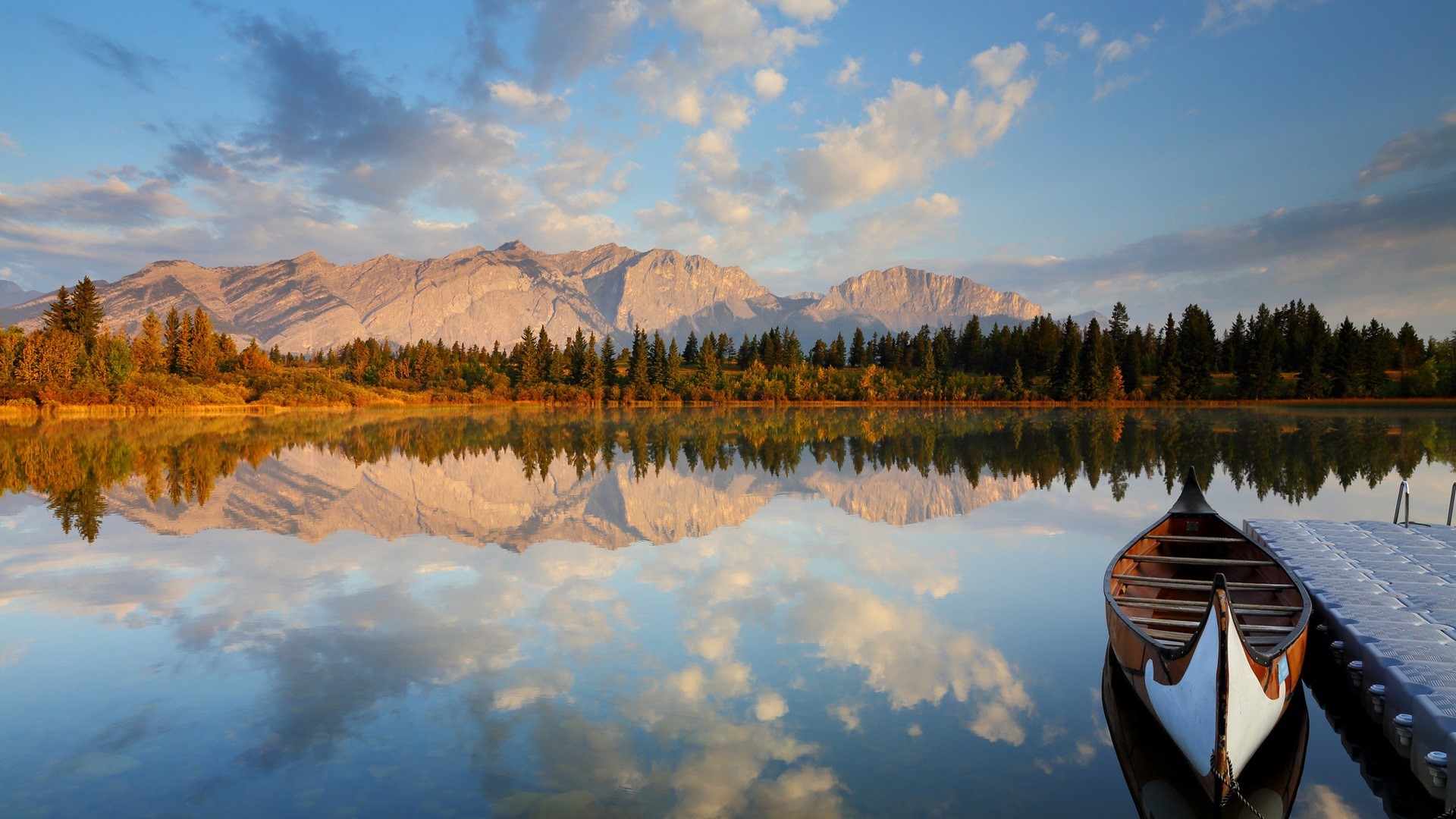 Canoe on a calm lake with mountains and forest reflection HD Wallpaper