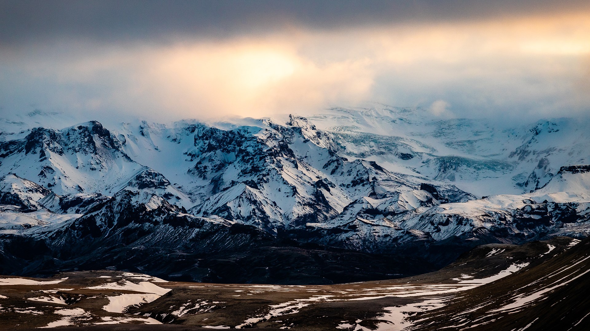 Snowy mountains under dramatic clouds HD Wallpaper