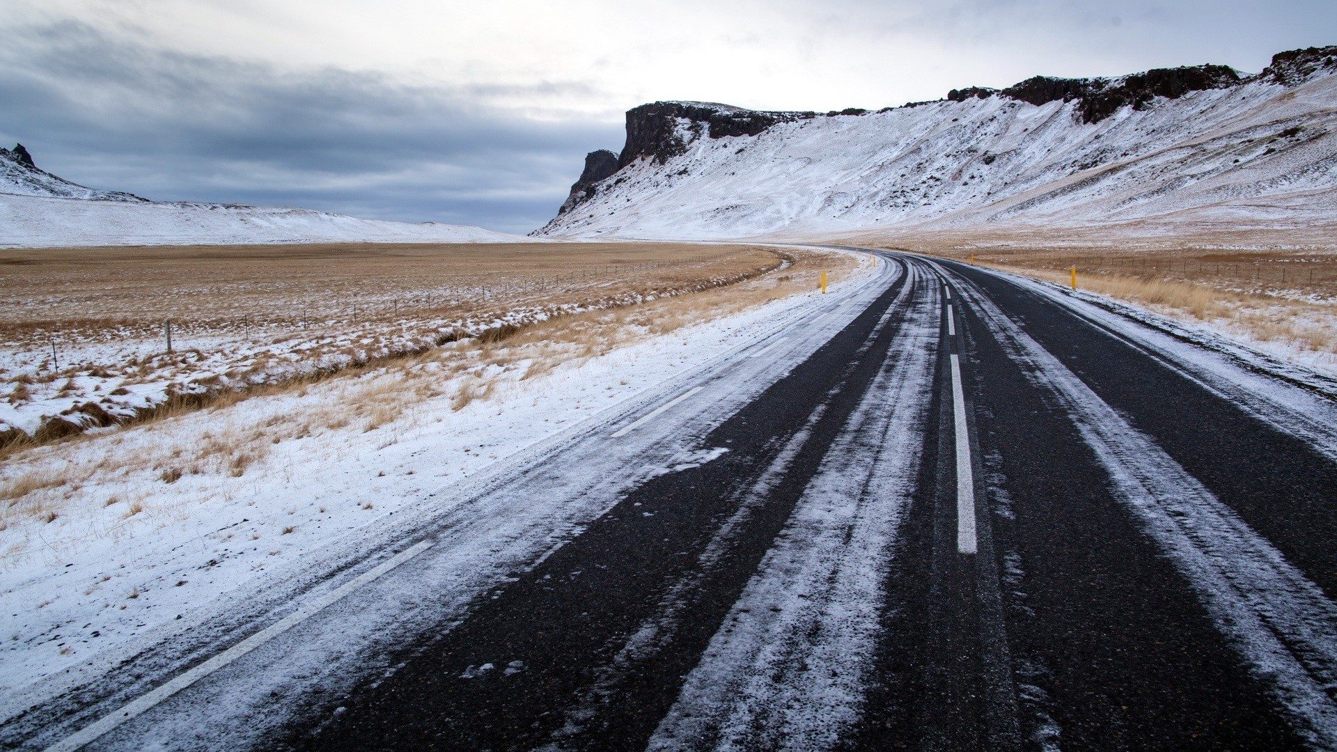 Snowy road through a winter landscape with mountains HD Wallpaper