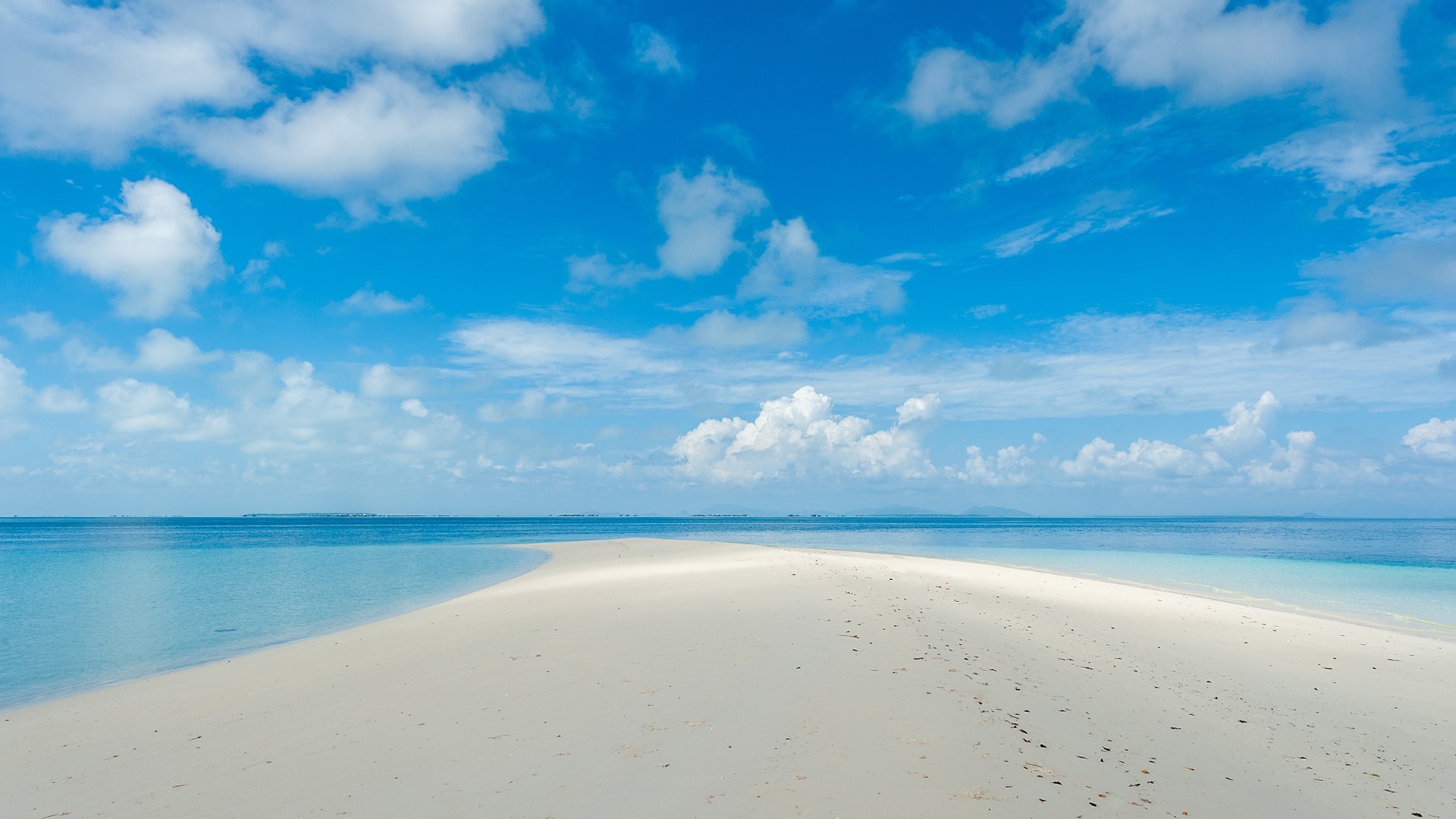 Sandbar extending into the ocean under a blue sky with clouds HD Wallpaper