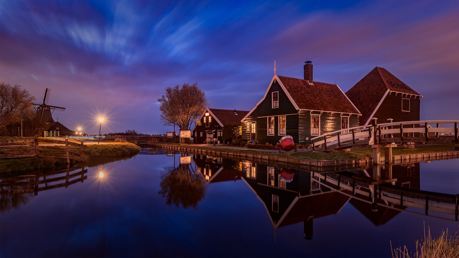 Dutch windmills and houses reflected in water at night HD Wallpaper