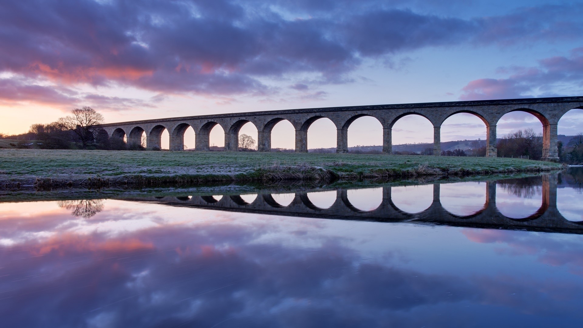 Stone viaduct reflected in water at sunset HD Wallpaper