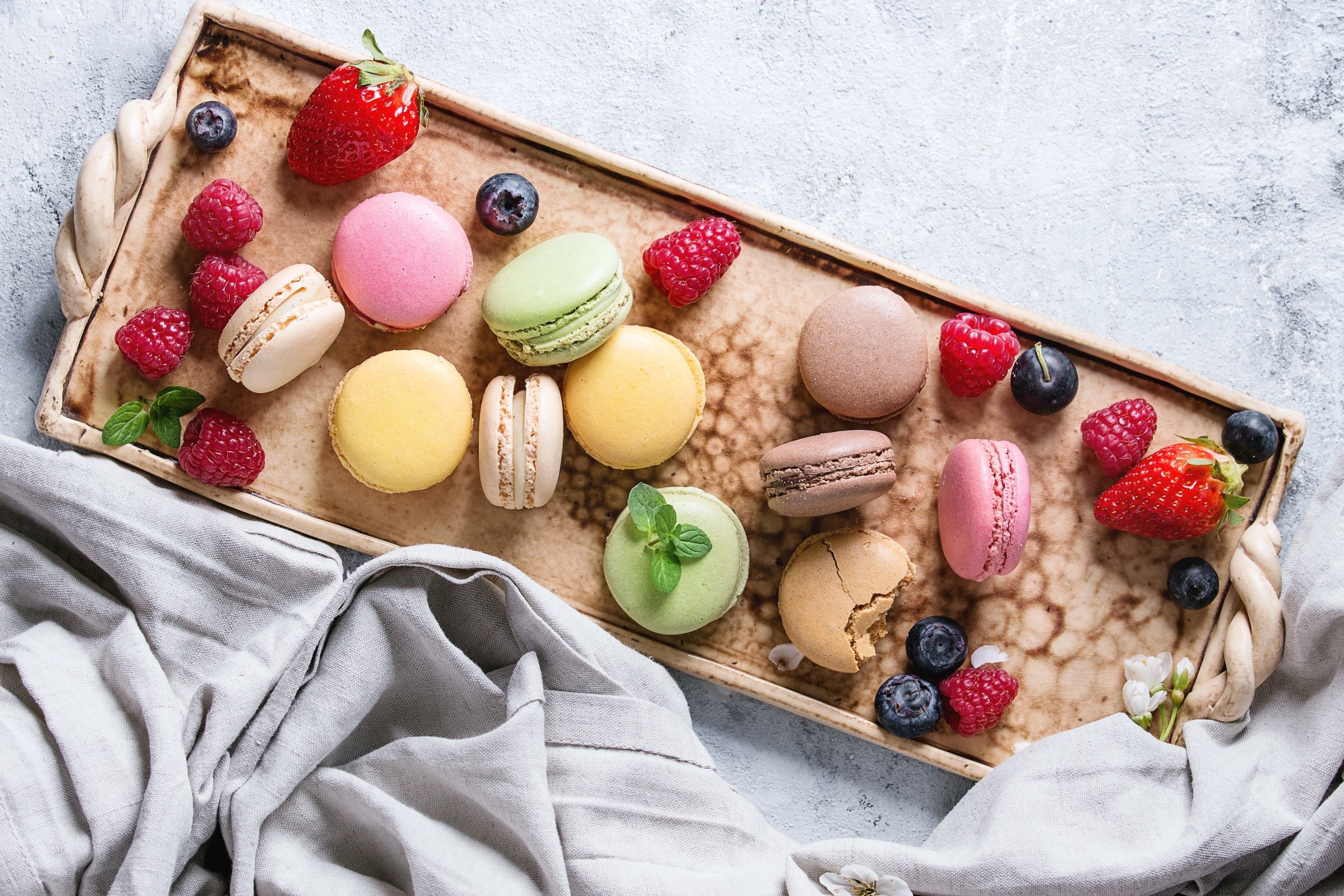 Assortment of colorful macarons and fresh berries on a tray HD Wallpaper