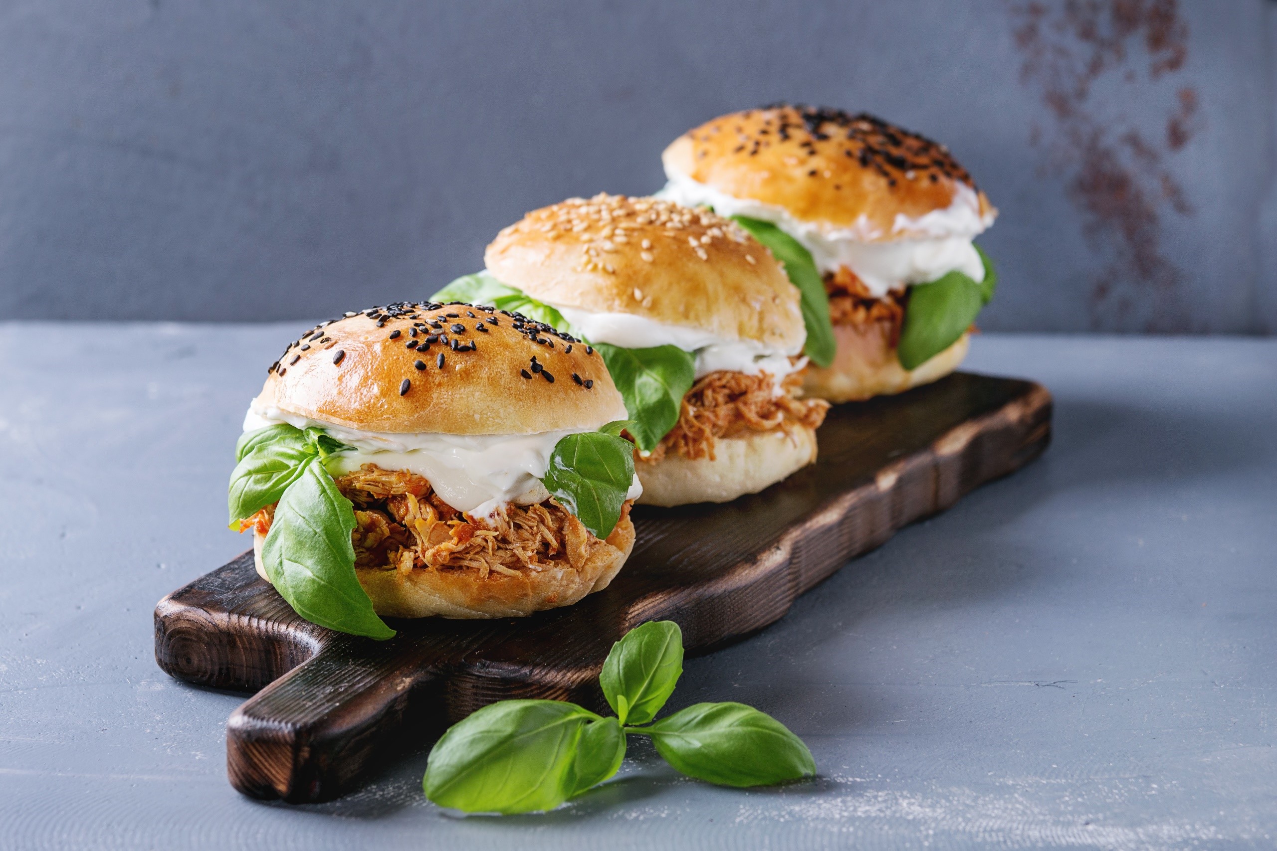 Three pulled pork sandwiches with basil on a wooden board HD Wallpaper