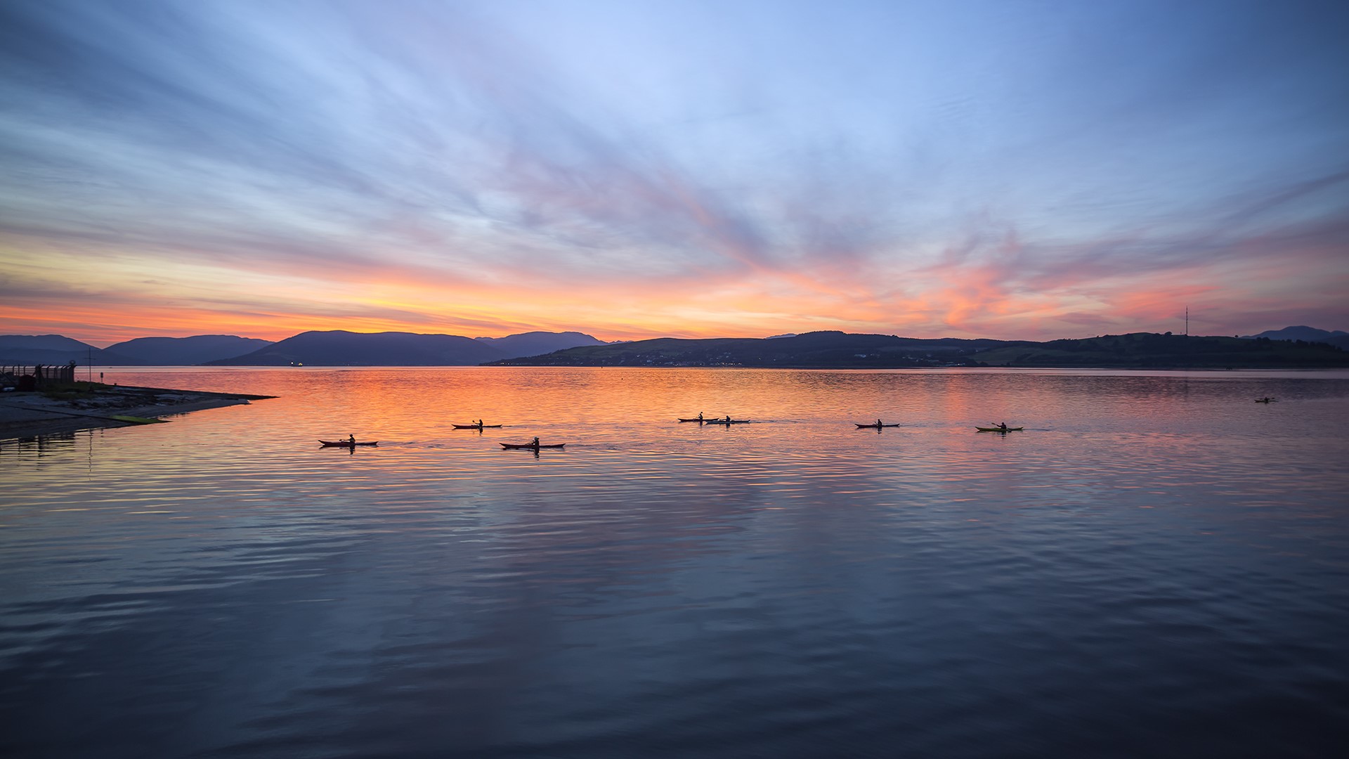 Kayakers on a lake at sunset with mountains in the background HD Wallpaper
