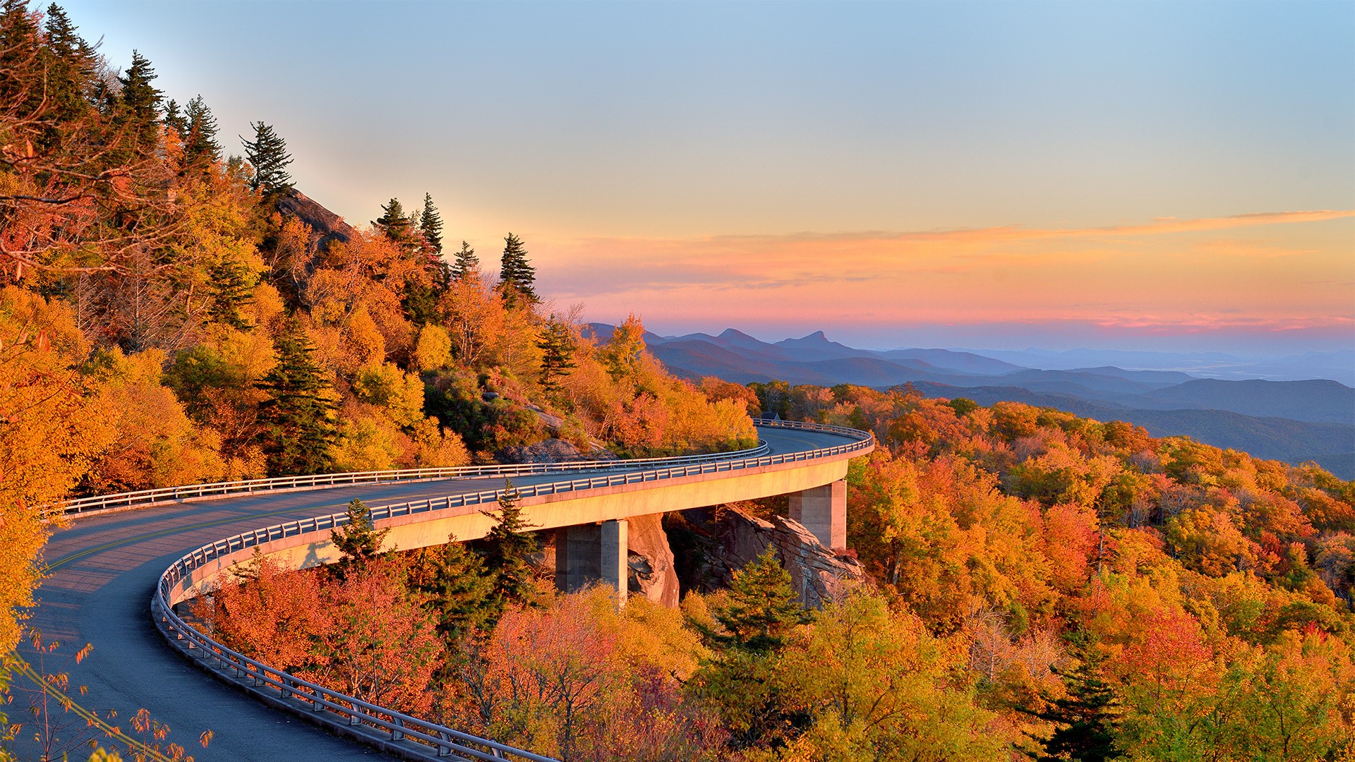 Scenic mountain road with autumn foliage and sunset HD Wallpaper