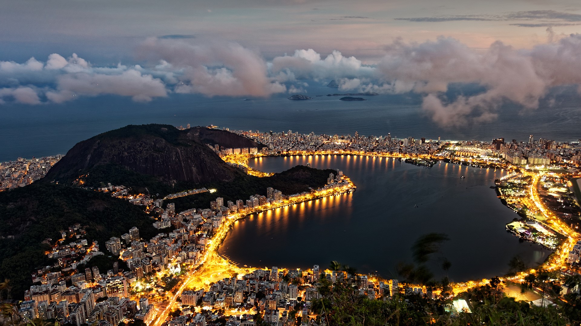 Cityscape of Rio de Janeiro at night with lake and mountains HD Wallpaper