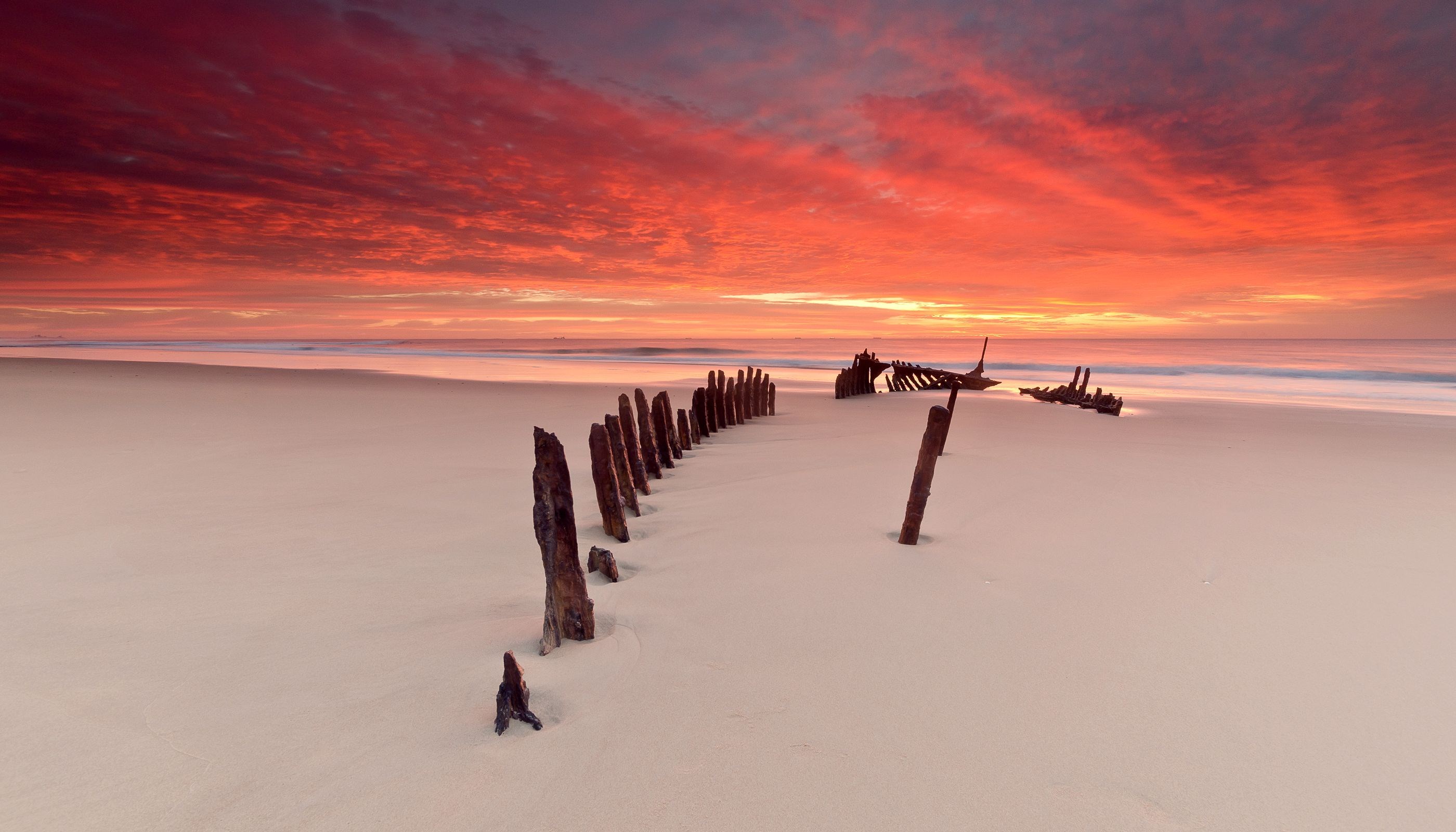 Shipwreck remains on a beach at sunset HD Wallpaper
