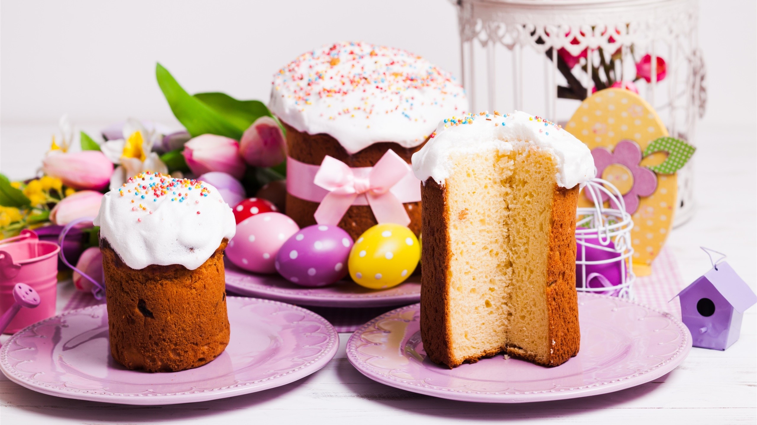 Easter cakes with whipped cream and sprinkles on plates with tulips and eggs HD Wallpaper