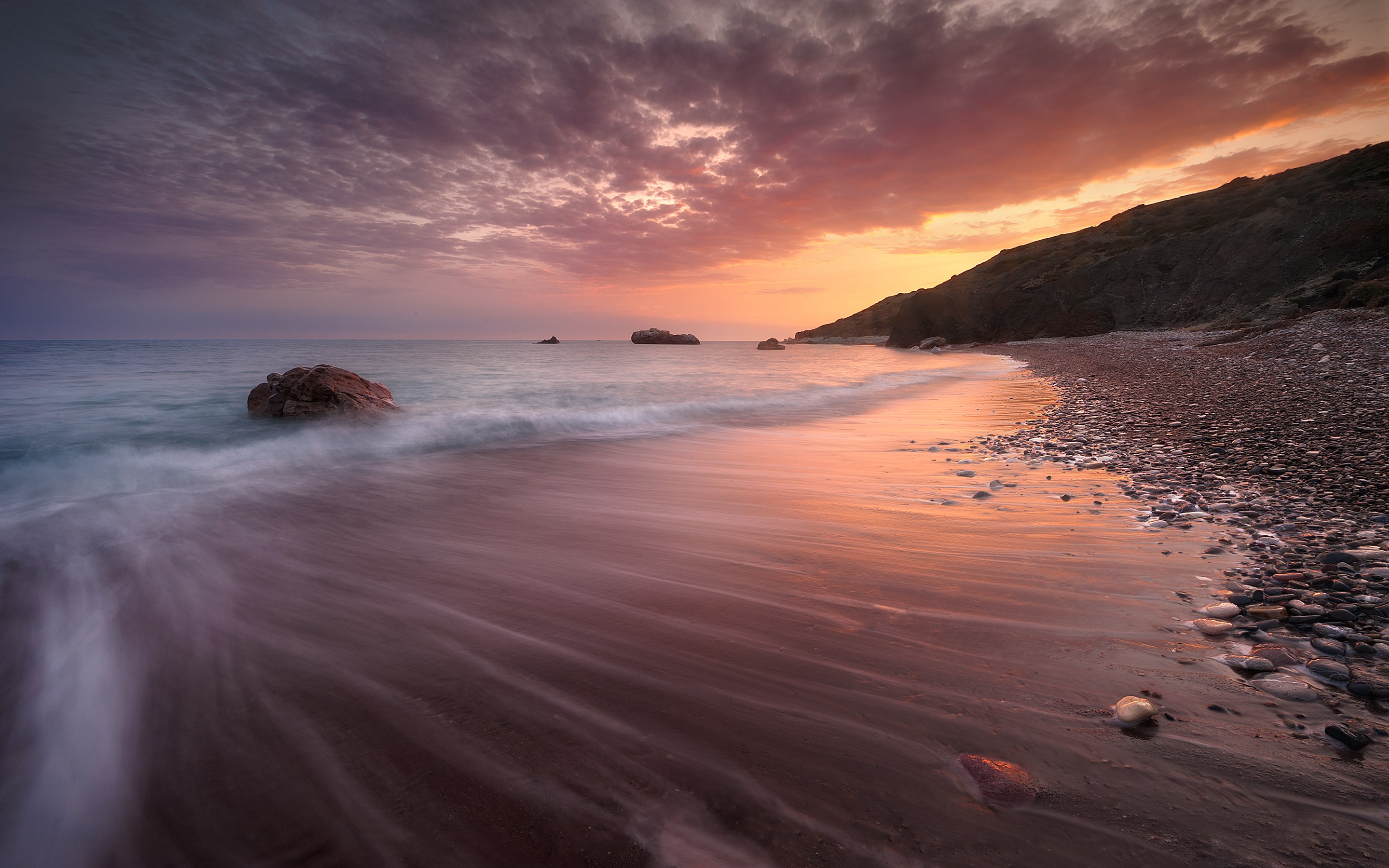 Sunset over a rocky beach with waves HD Wallpaper