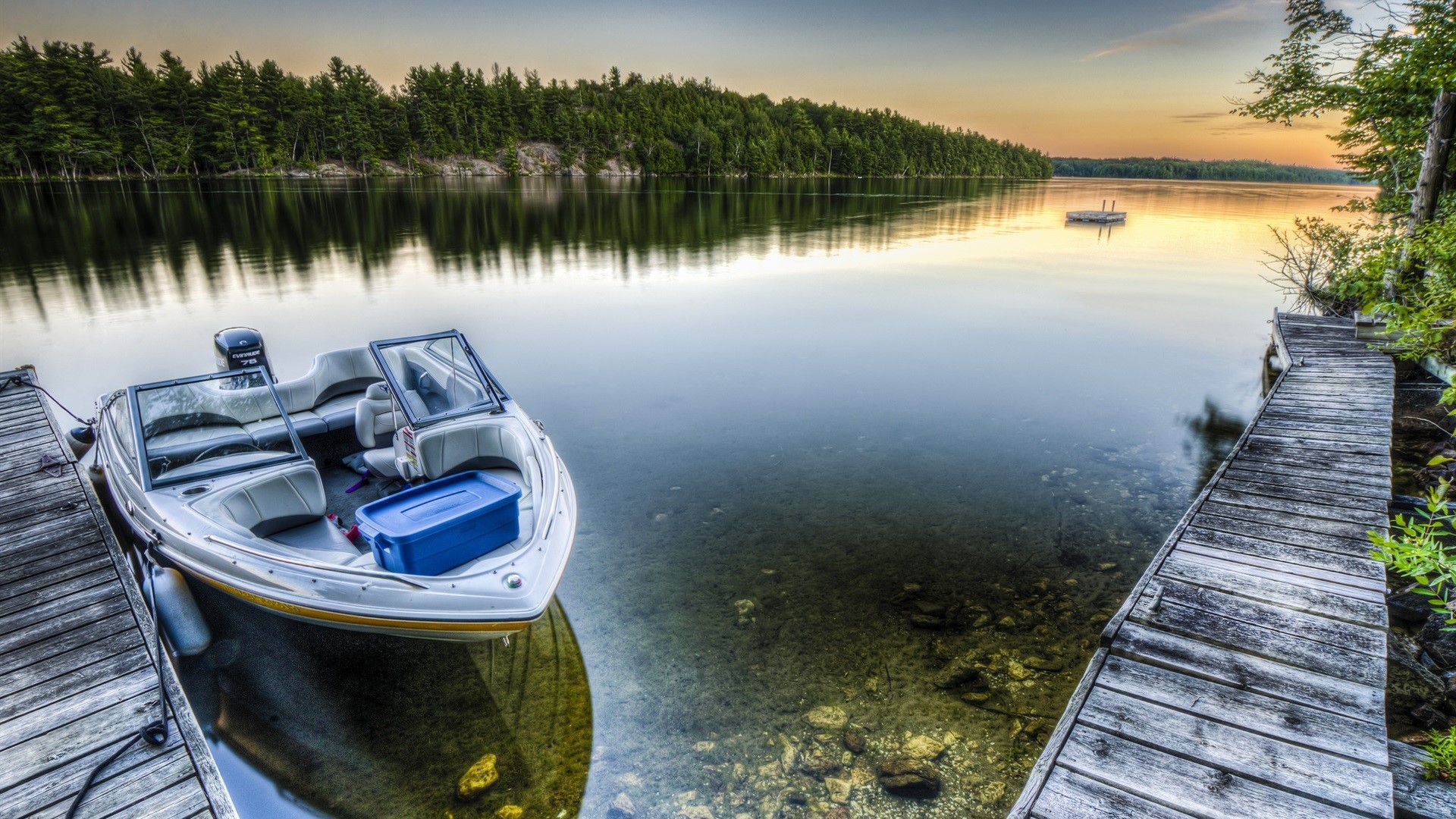 Boat docked on a lake at sunset with forest background HD Wallpaper