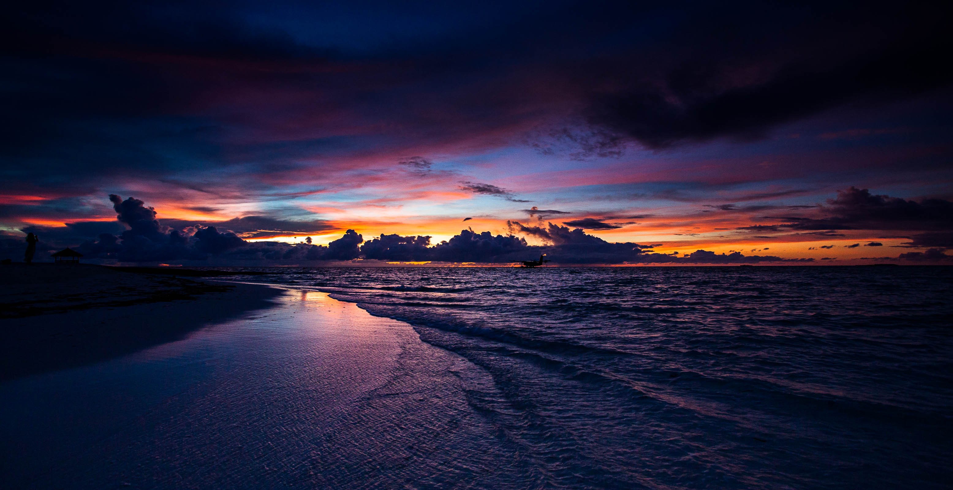 Beach at sunset with colorful clouds and ocean waves HD Wallpaper
