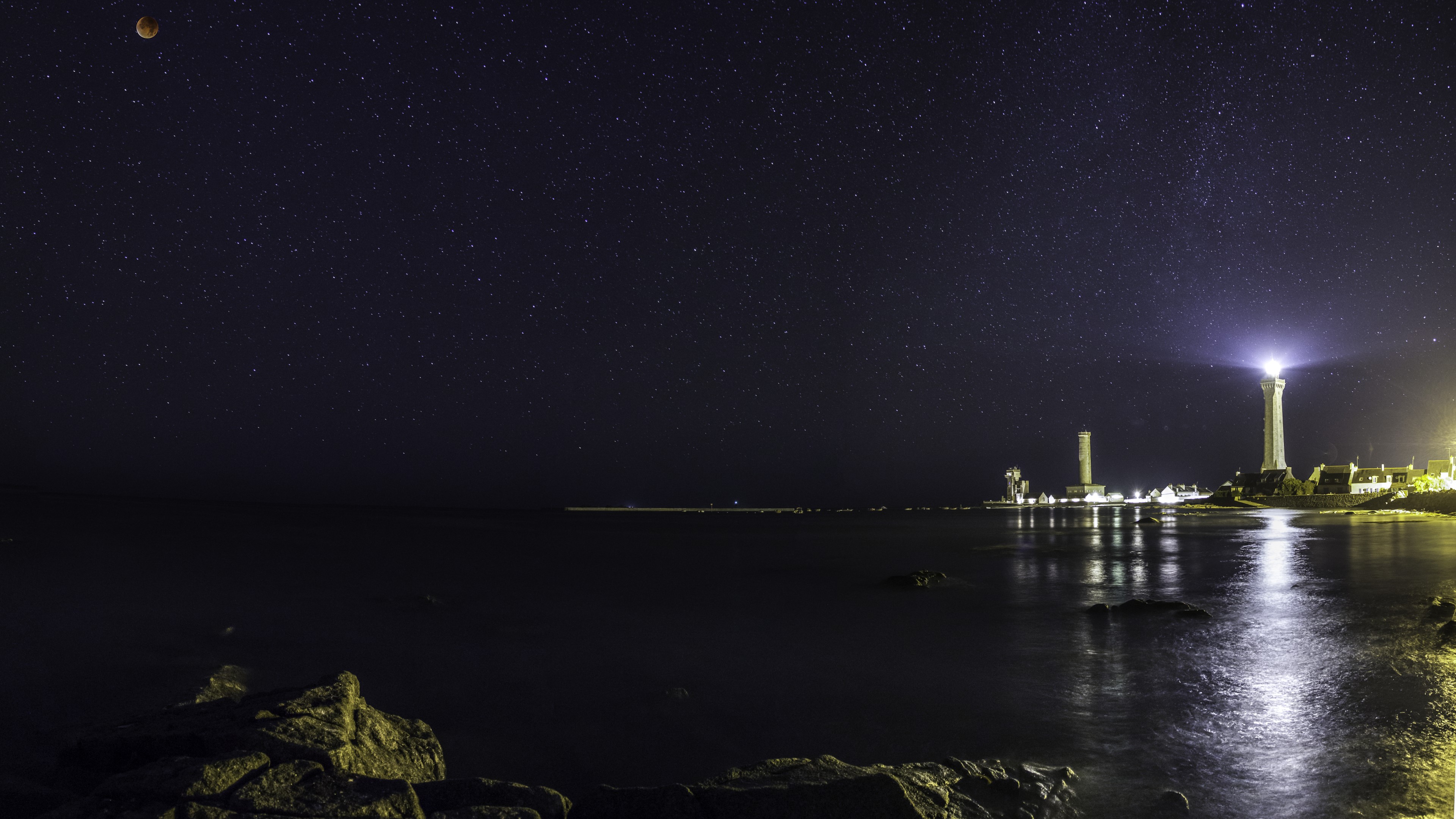 Lighthouse and stars over the sea at night HD Wallpaper
