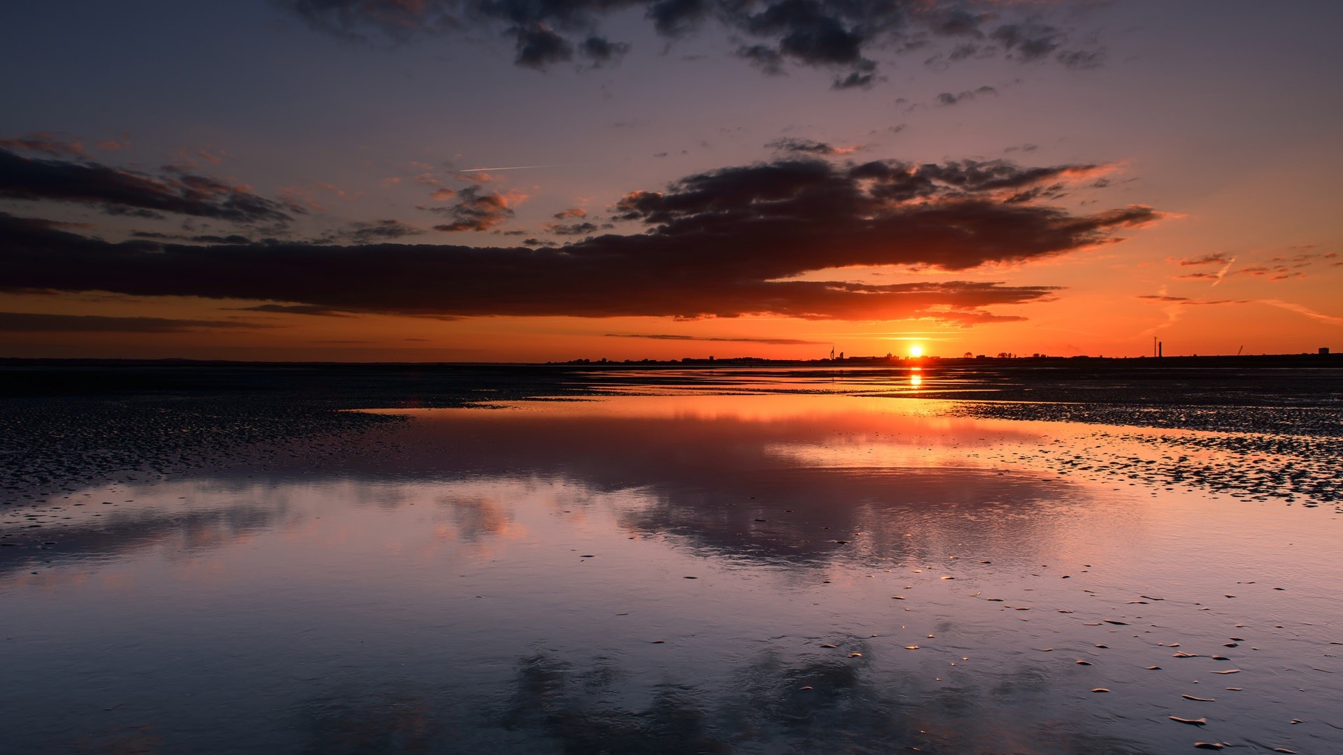 Sunset over a reflective body of water with clouds HD Wallpaper