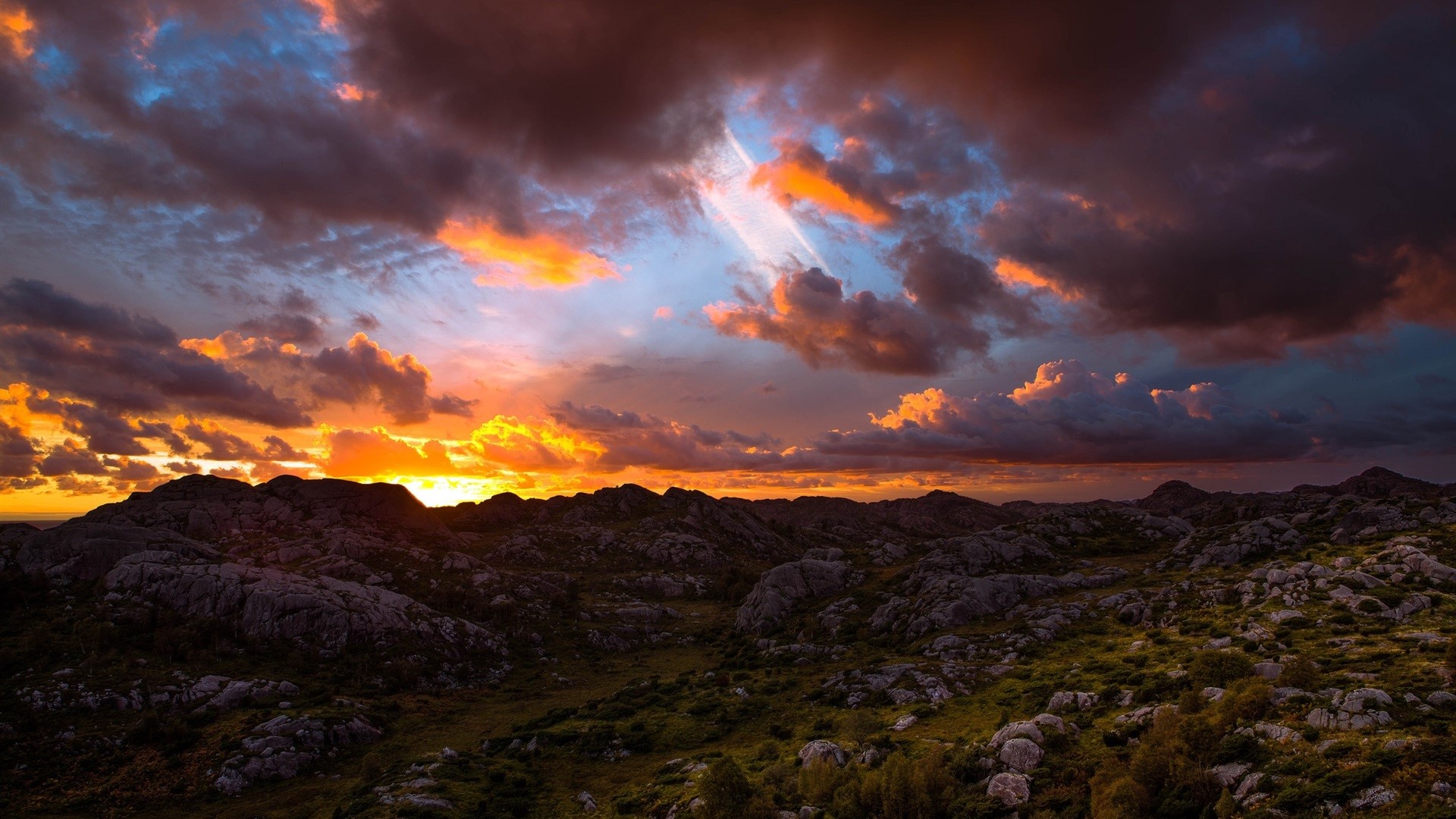 Dramatic sunset over rocky landscape with clouds HD Wallpaper