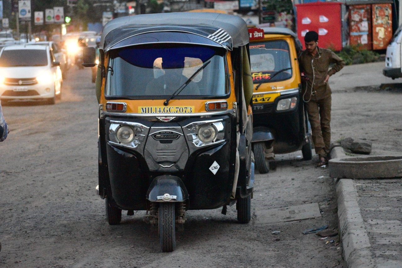 Two auto-rickshaws on a street with a man standing HD Wallpaper