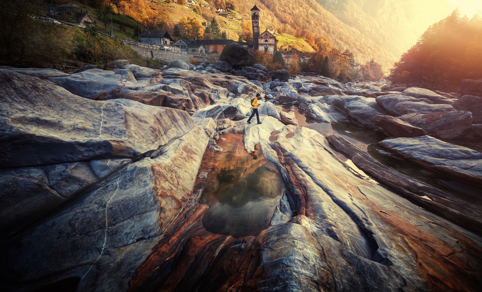 Person walking on rocks in a mountain village during fall HD Wallpaper