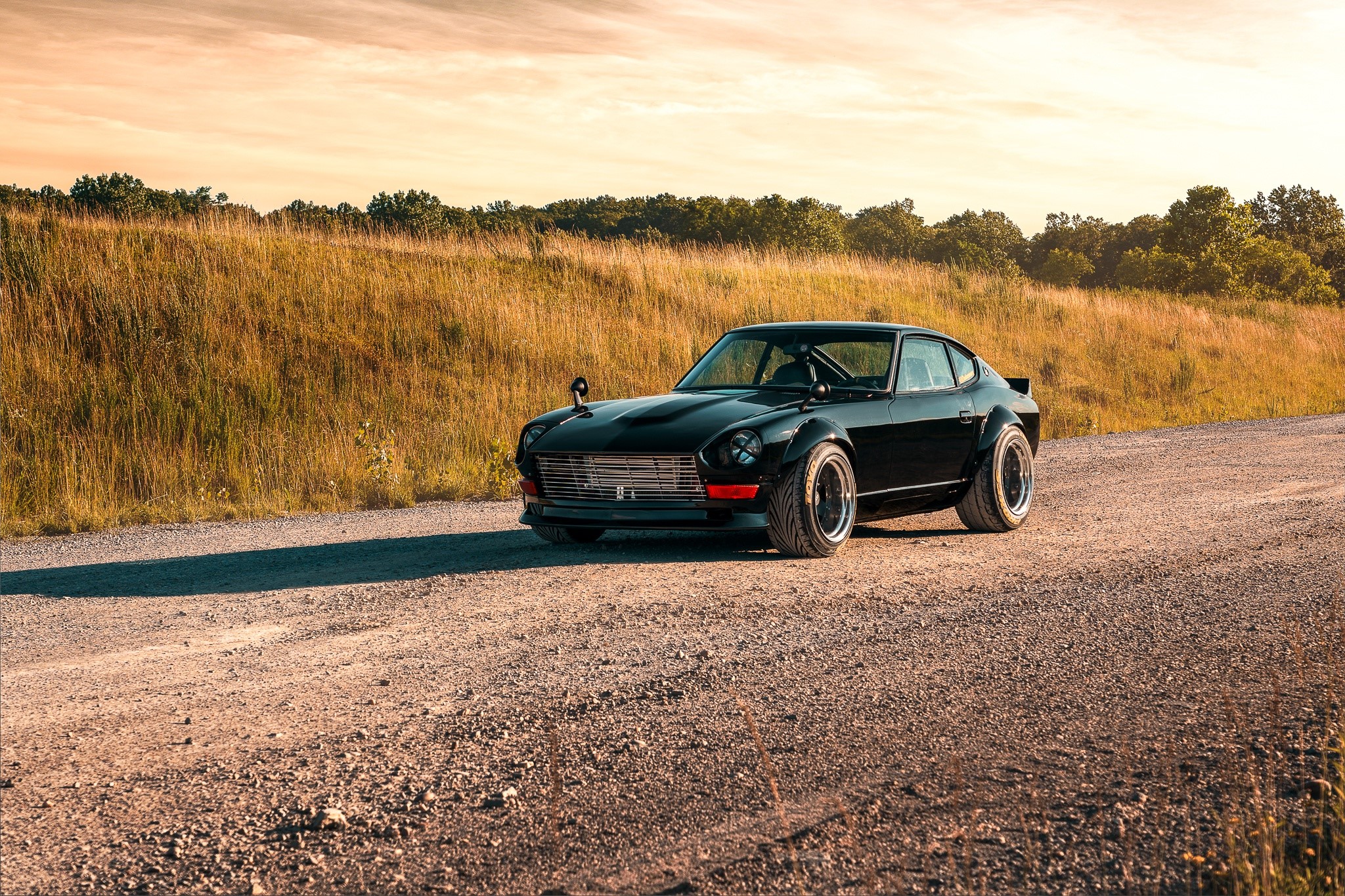 Black Datsun 240Z with bolt-on fender flares on a dirt road HD Wallpaper