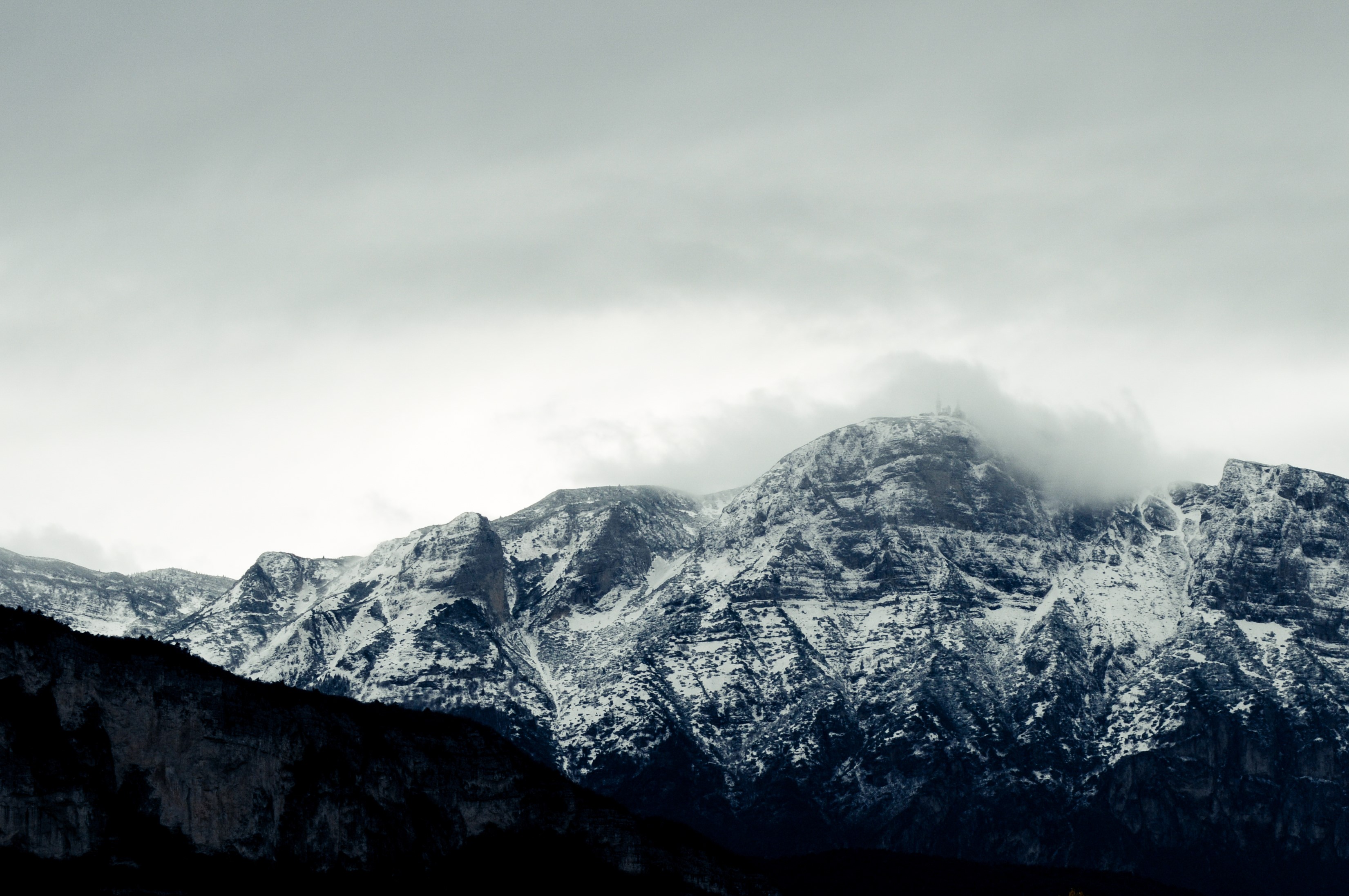 Snow-covered mountains under a cloudy sky HD Wallpaper