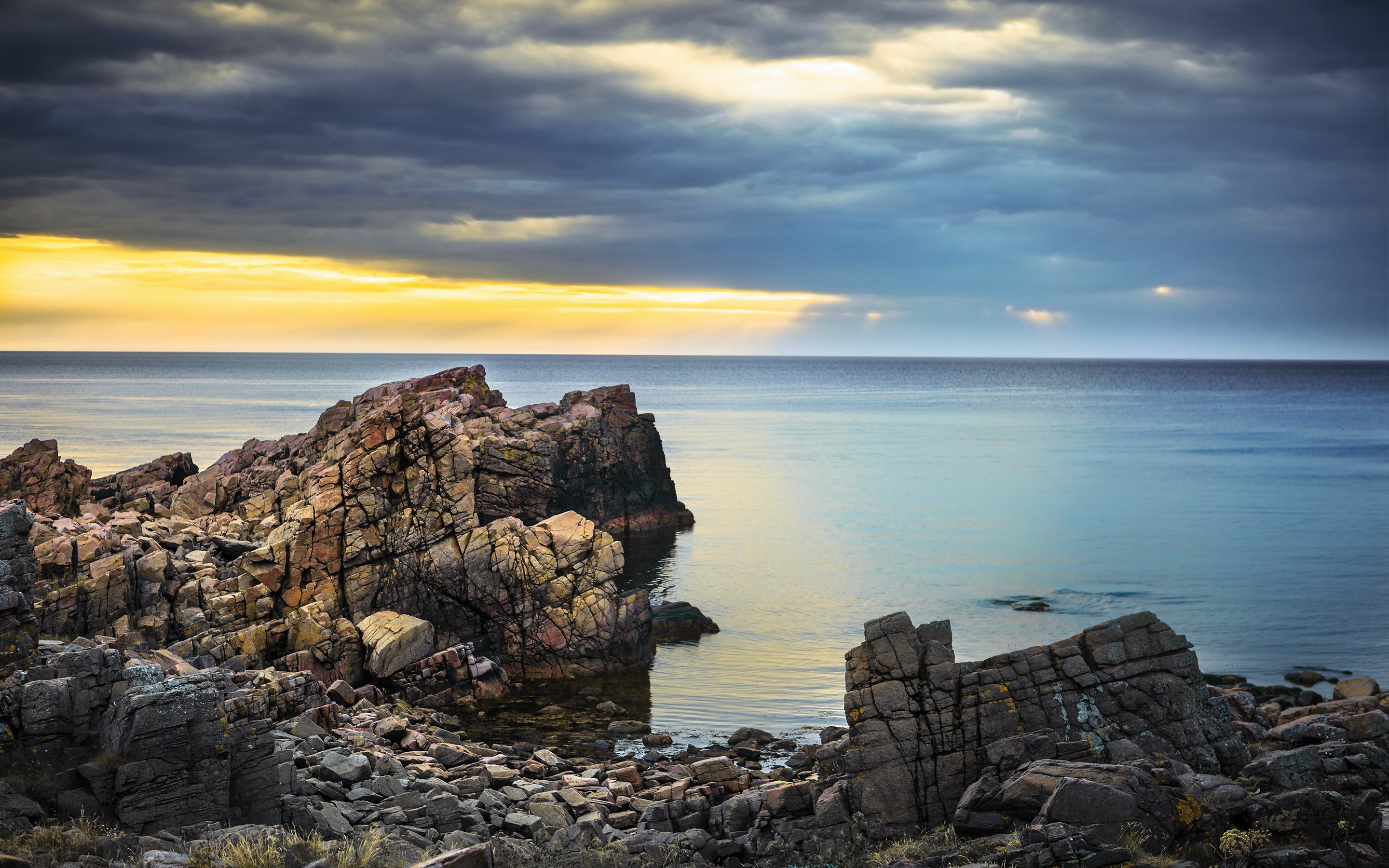 Rocky coastline with dramatic clouds over the sea HD Wallpaper