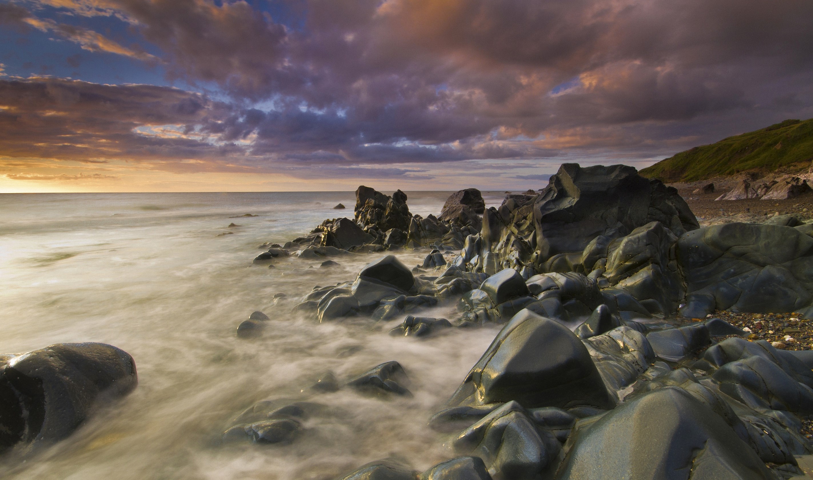 Rocky coastline with ocean waves at sunset HD Wallpaper