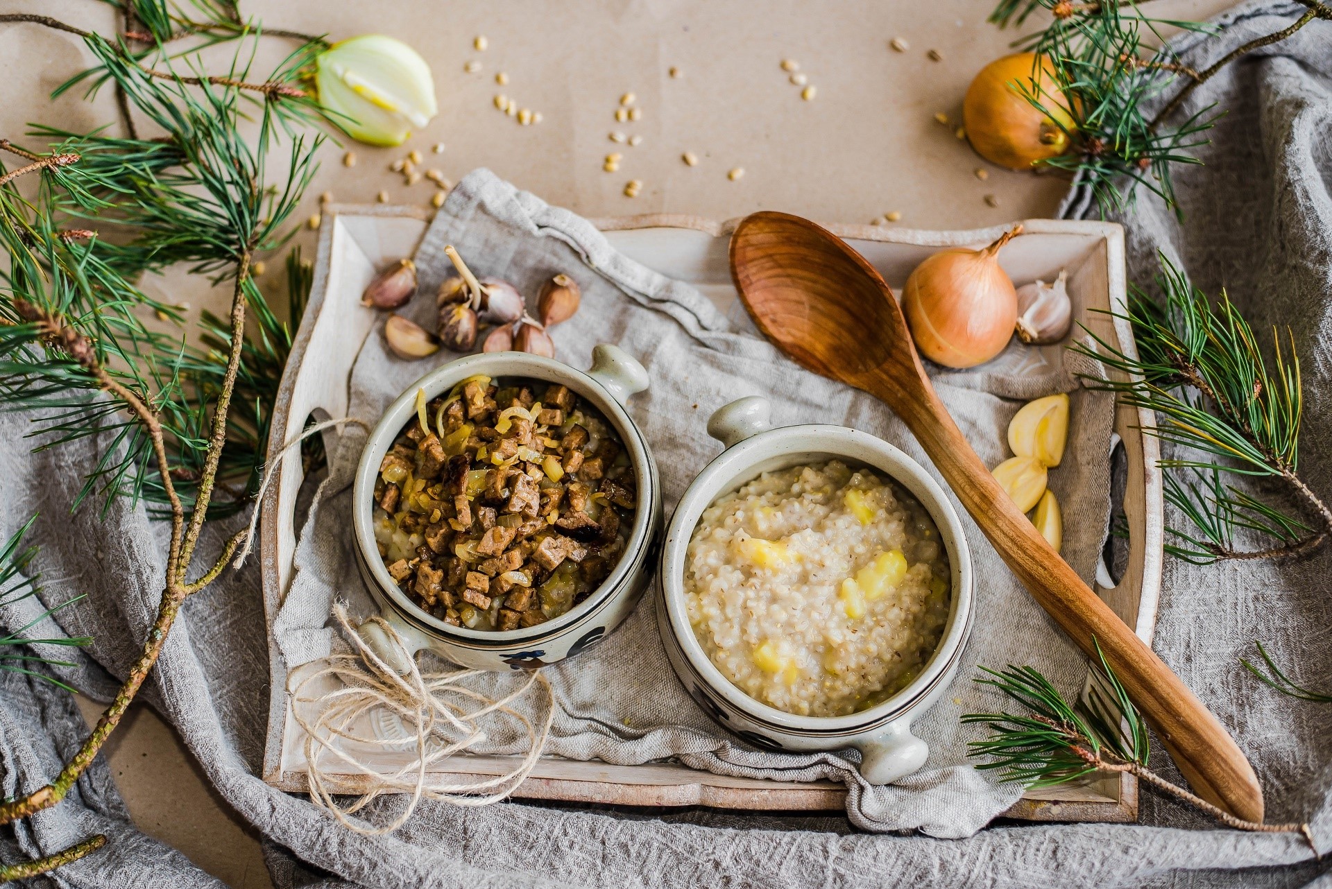 Two bowls of food with onions, garlic, and pine branches HD Wallpaper