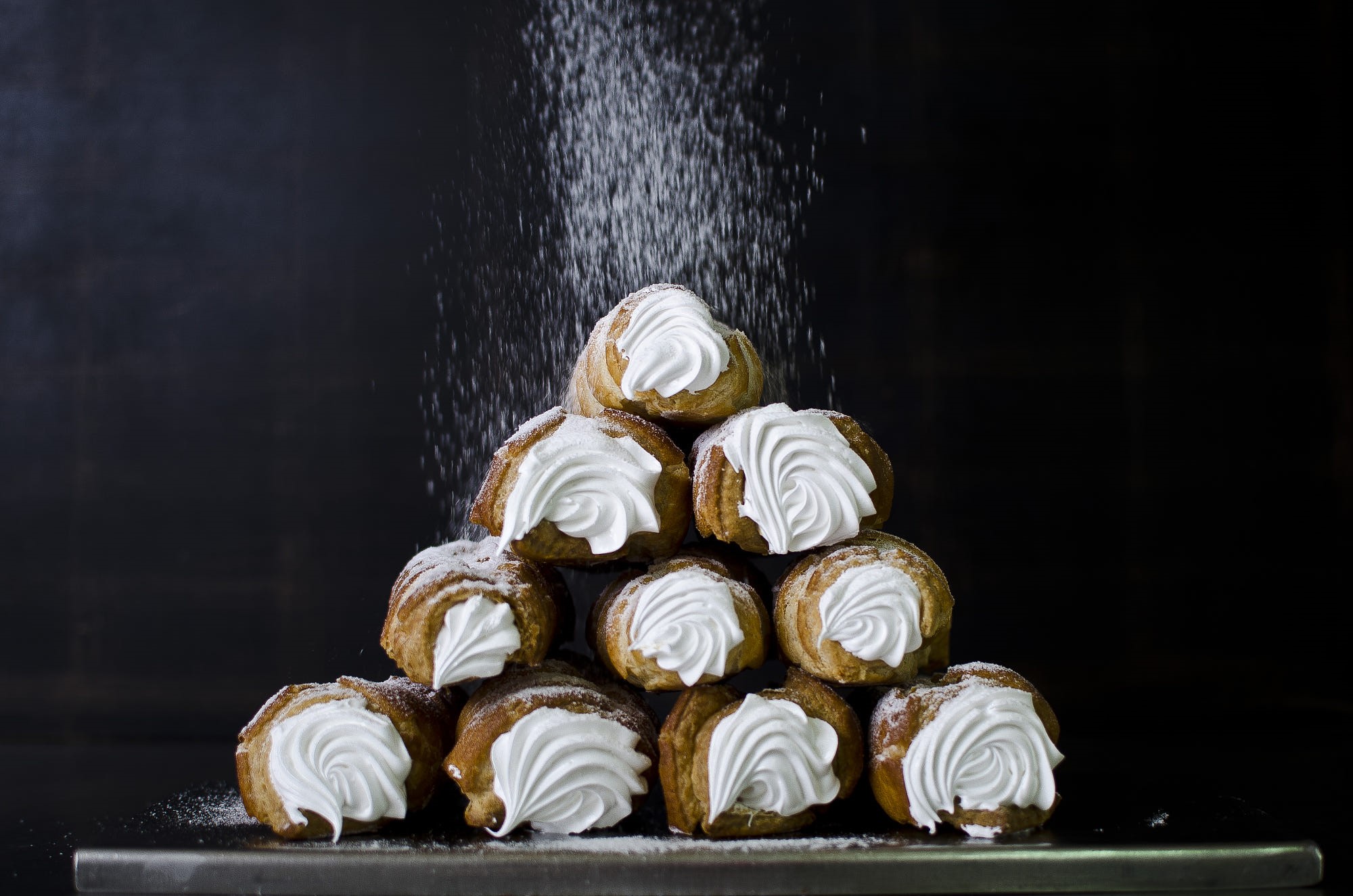 Pile of cream-filled pastries dusted with powdered sugar HD Wallpaper