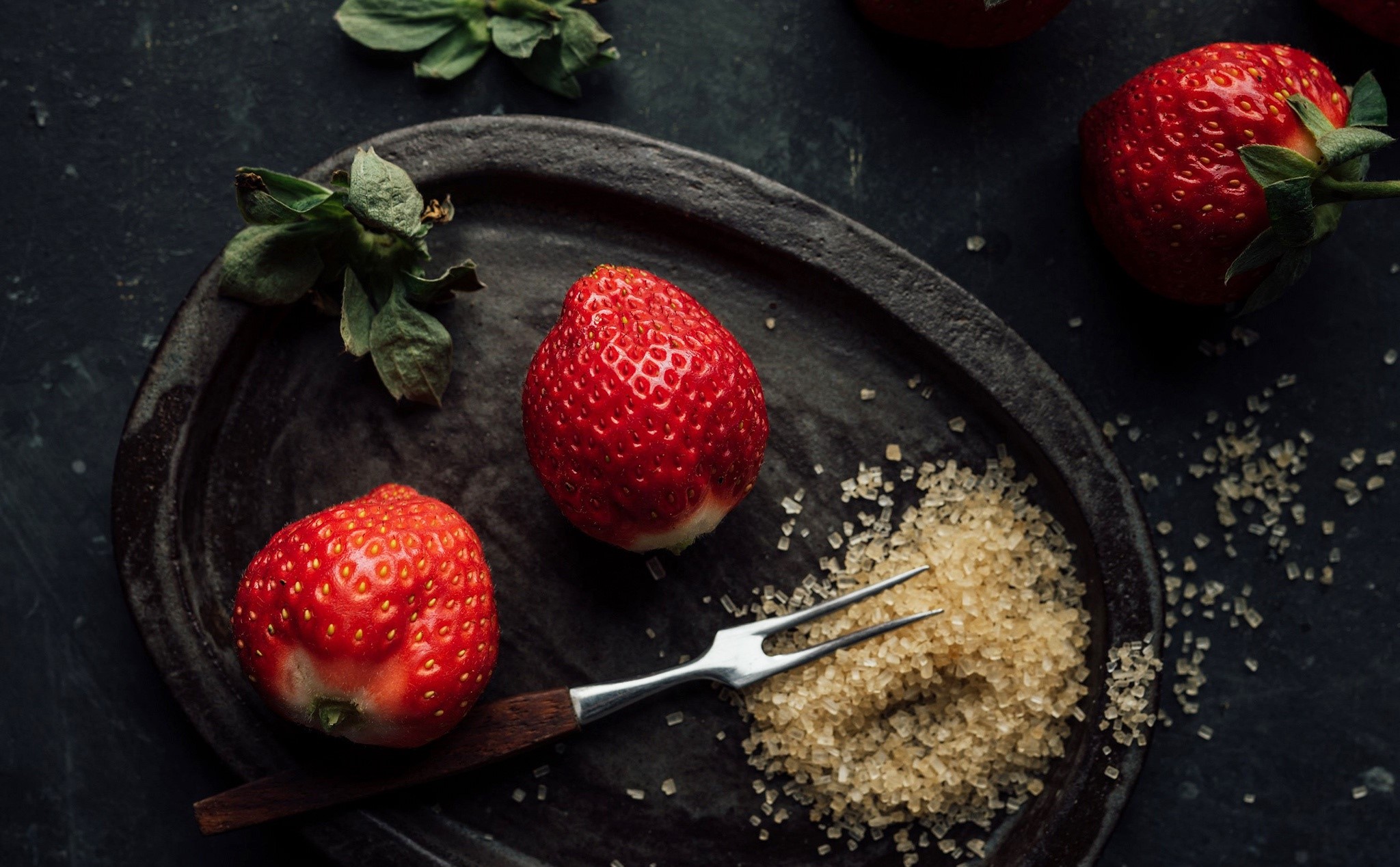 Strawberries with sugar and a fork on a dark plate HD Wallpaper