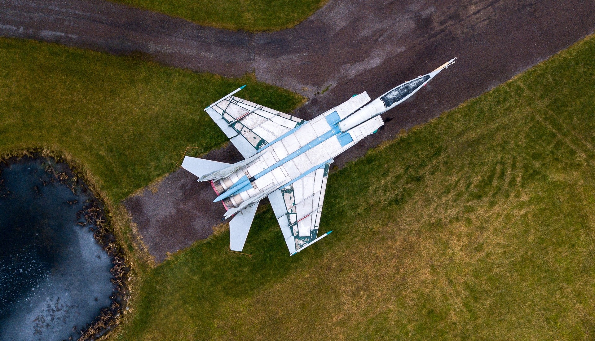 Mig-25 military aircraft on tarmac near pond HD Wallpaper