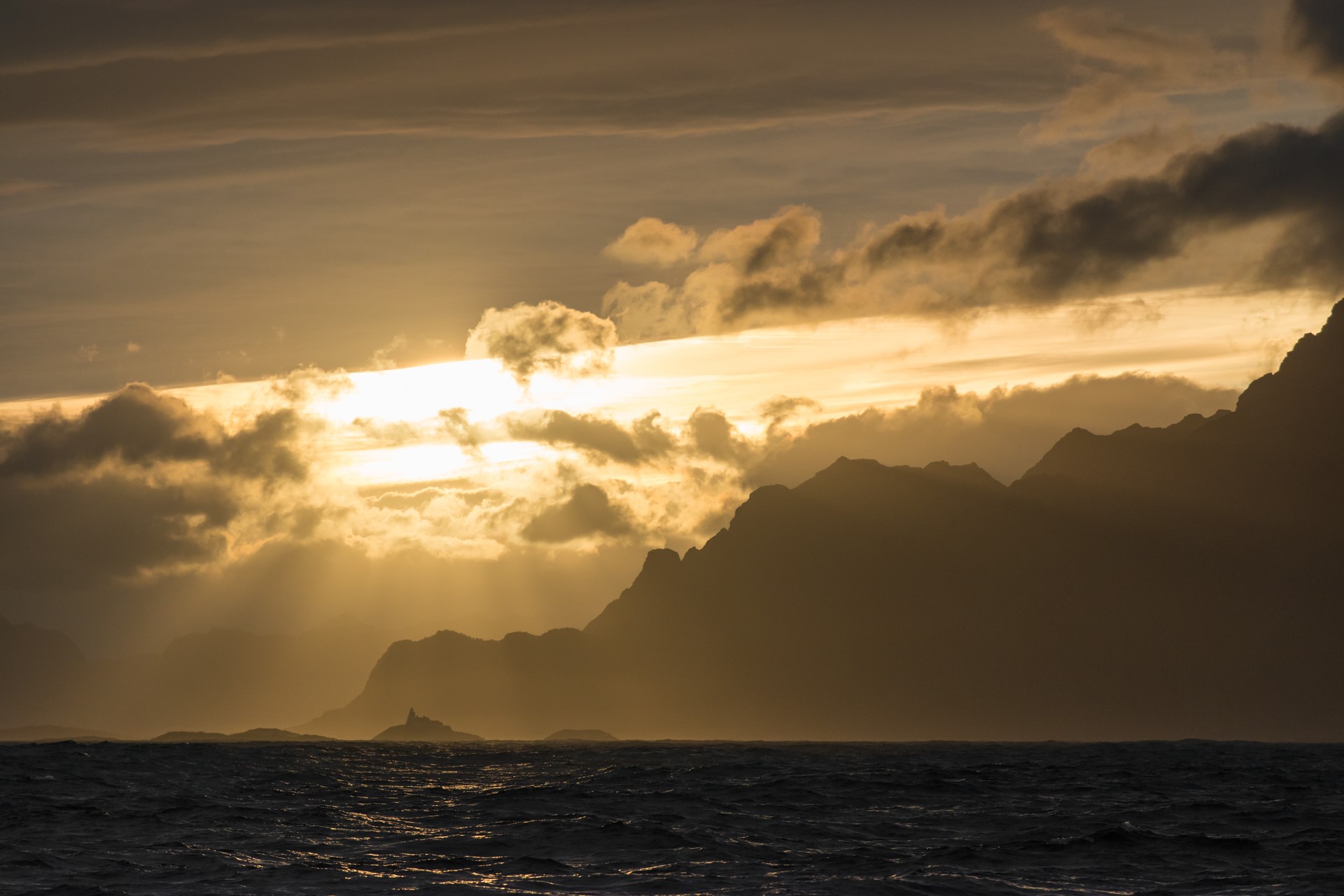 Sunlight breaking through clouds over mountains and sea HD Wallpaper